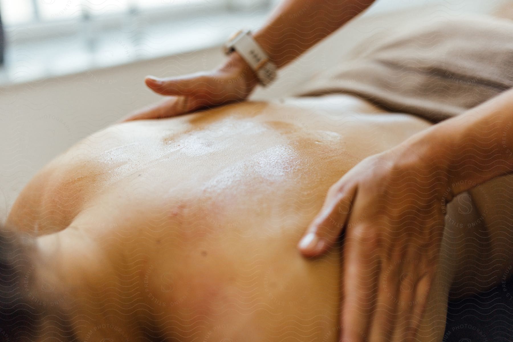 Hands massaging the bare back of a woman in a spa