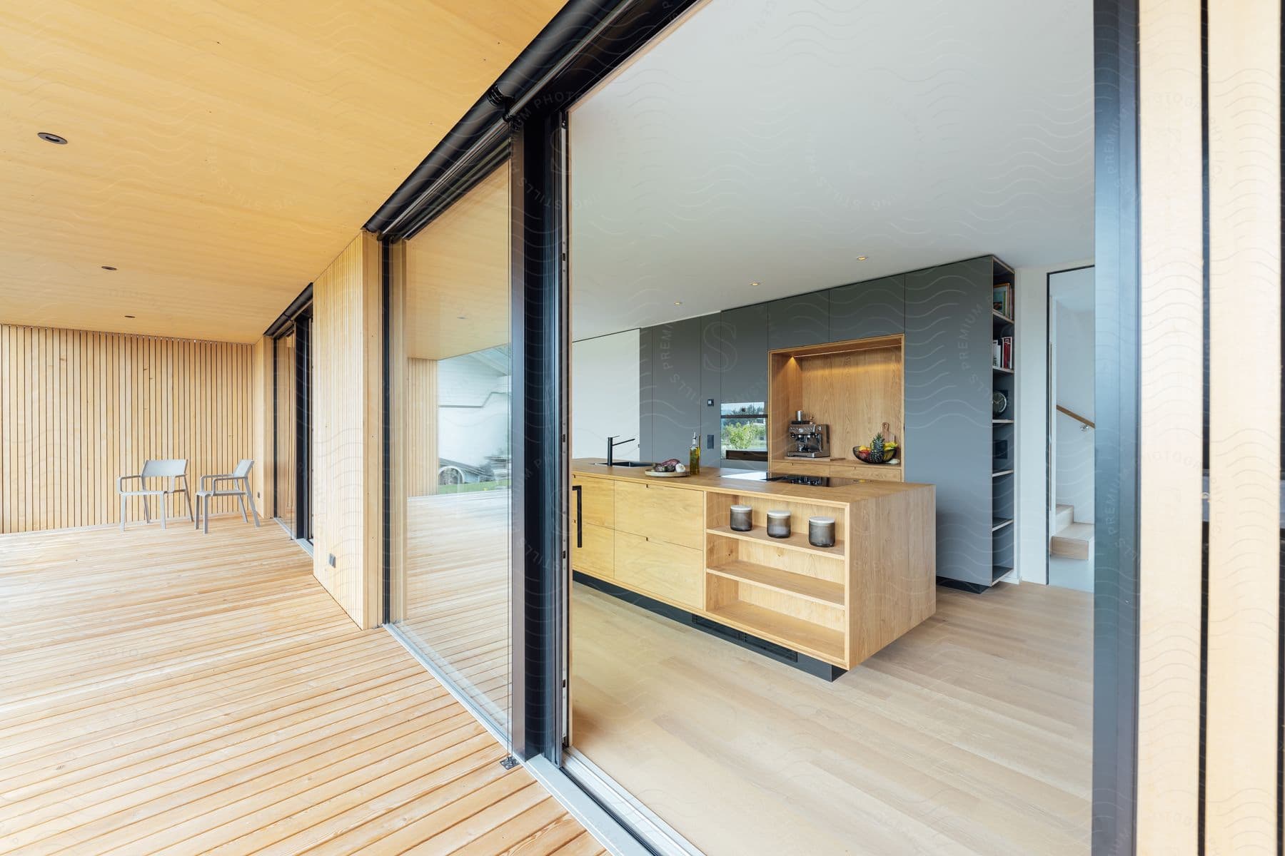 Warm wood floors flow into a kitchen, where a sliding glass door opens to a deck with a table and chairs.