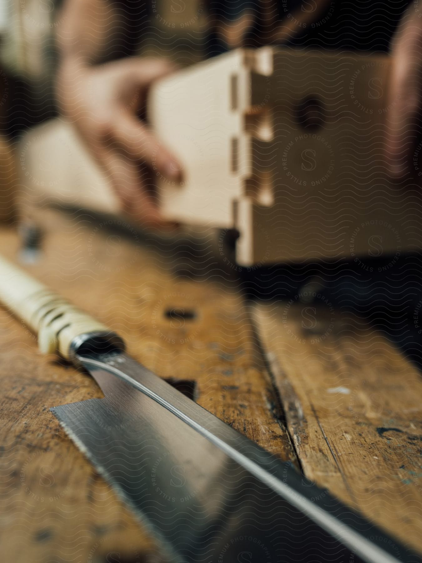 A knife is on the table as a person puts together a wooden box