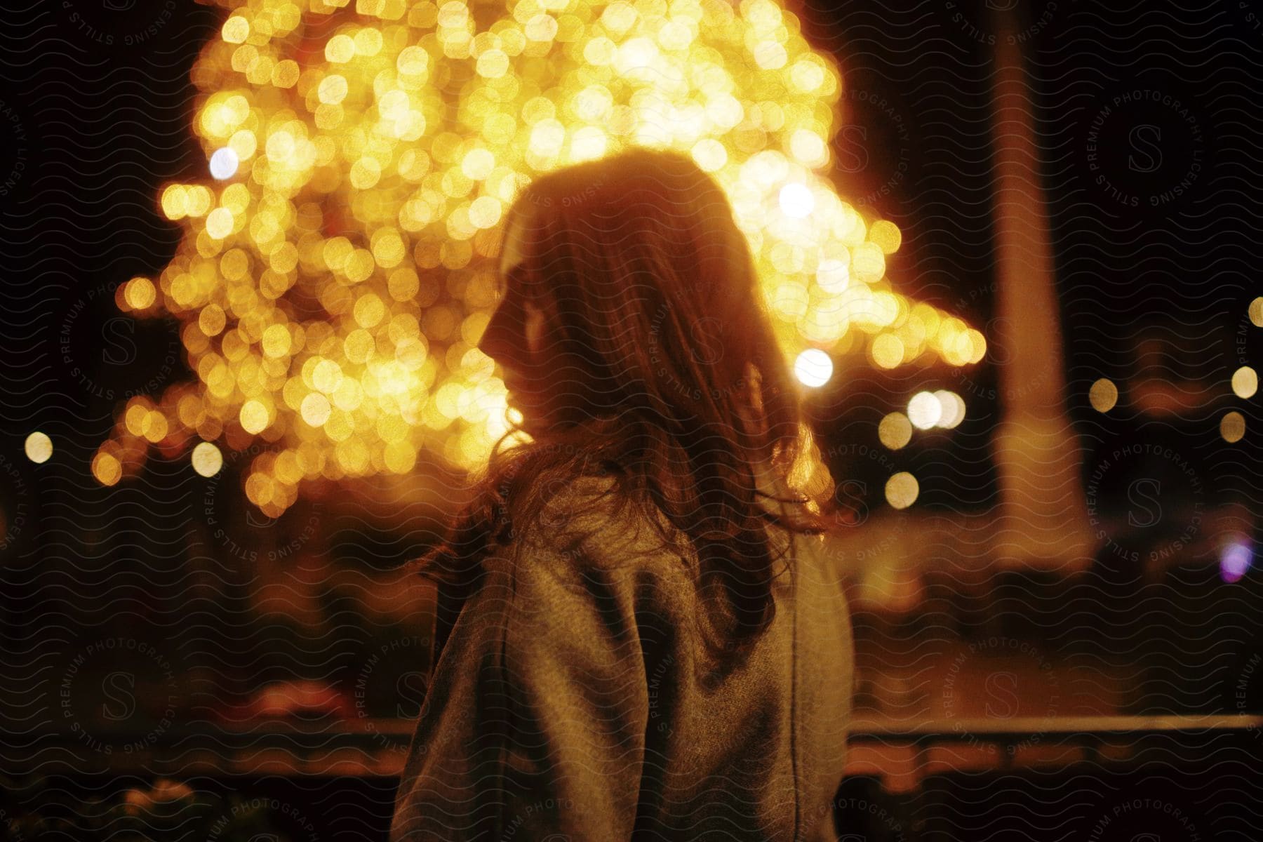 A woman outdoors at nighta at a firework display.