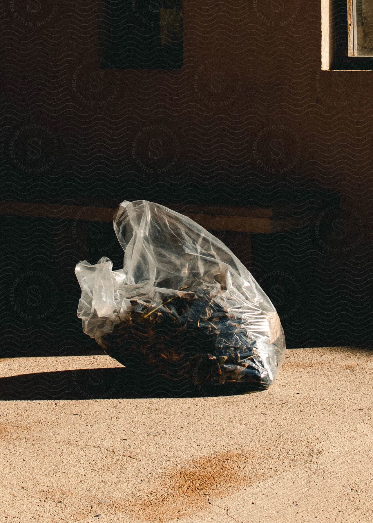 A bag full of objects is on the floor and receiving natural light