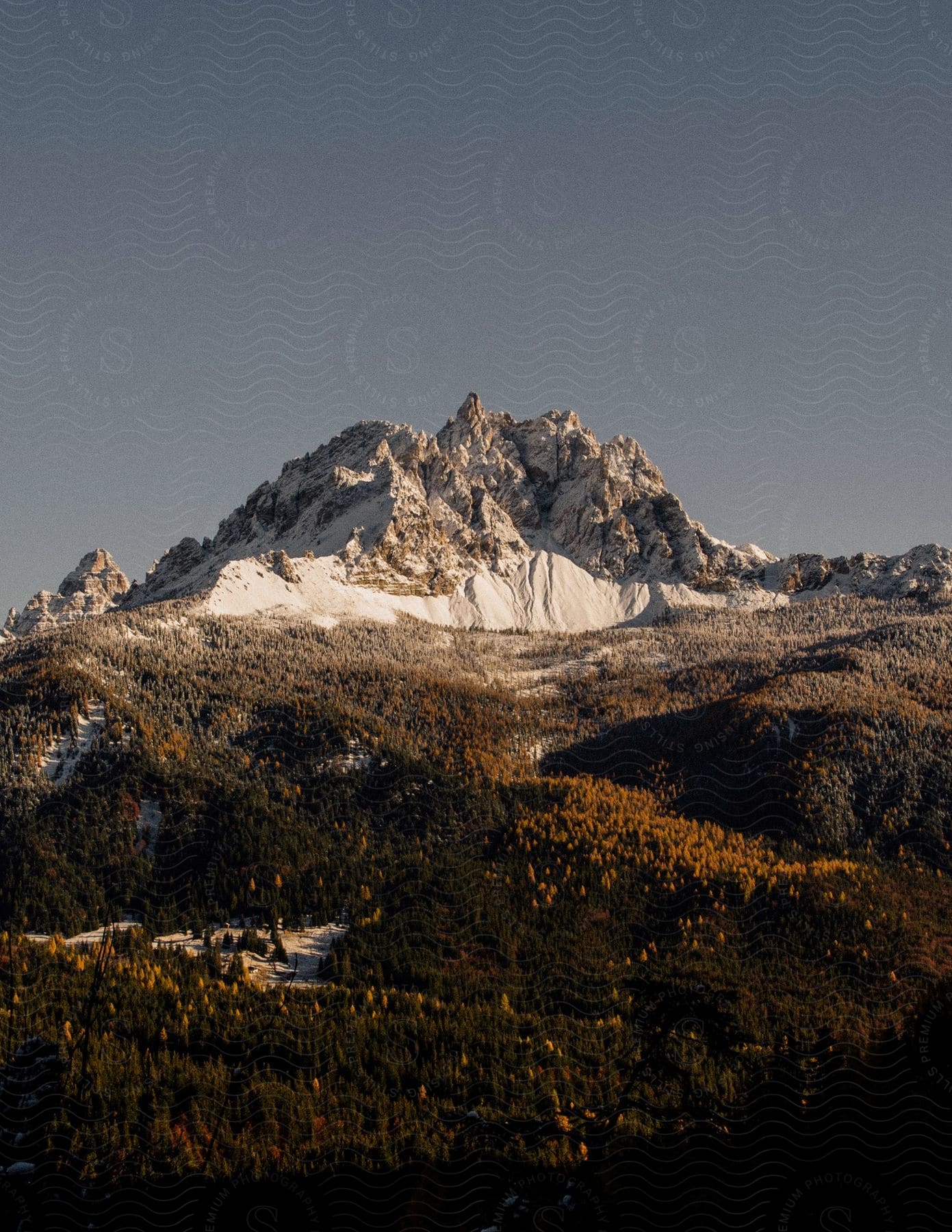 Snow covers a craggy mountain peak on a clear, sunny day.