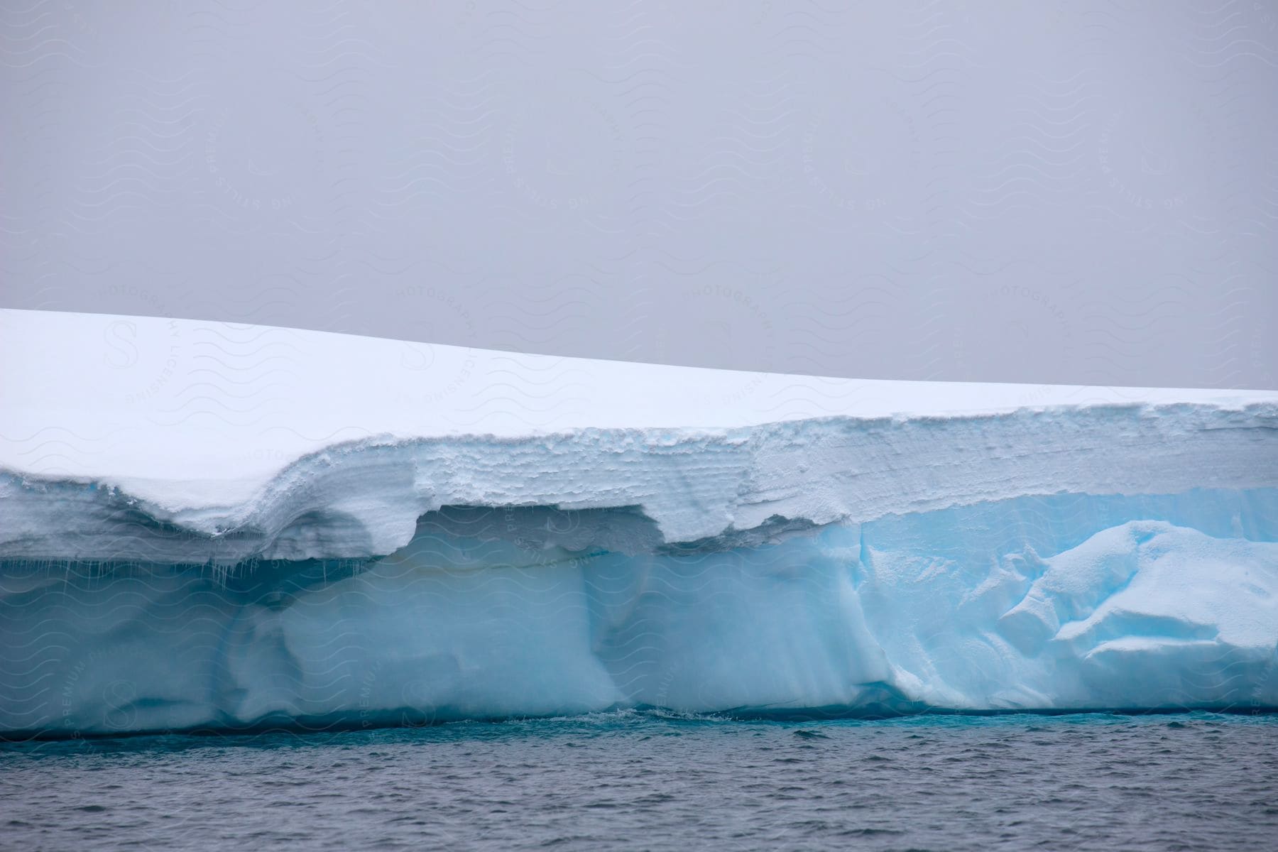 A large glacier covered in snow out on the edge of the sea