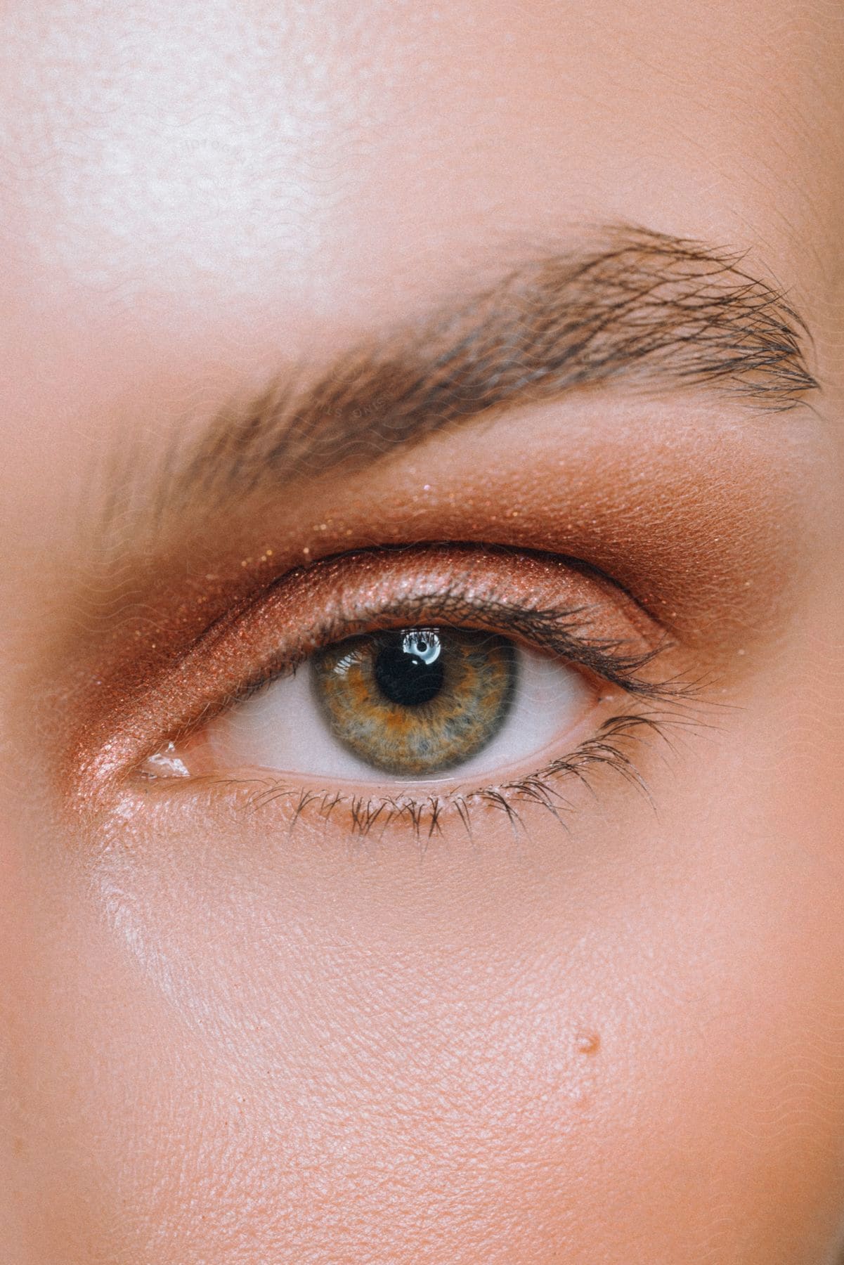 a female eye wearing makeup with gold eye shadow