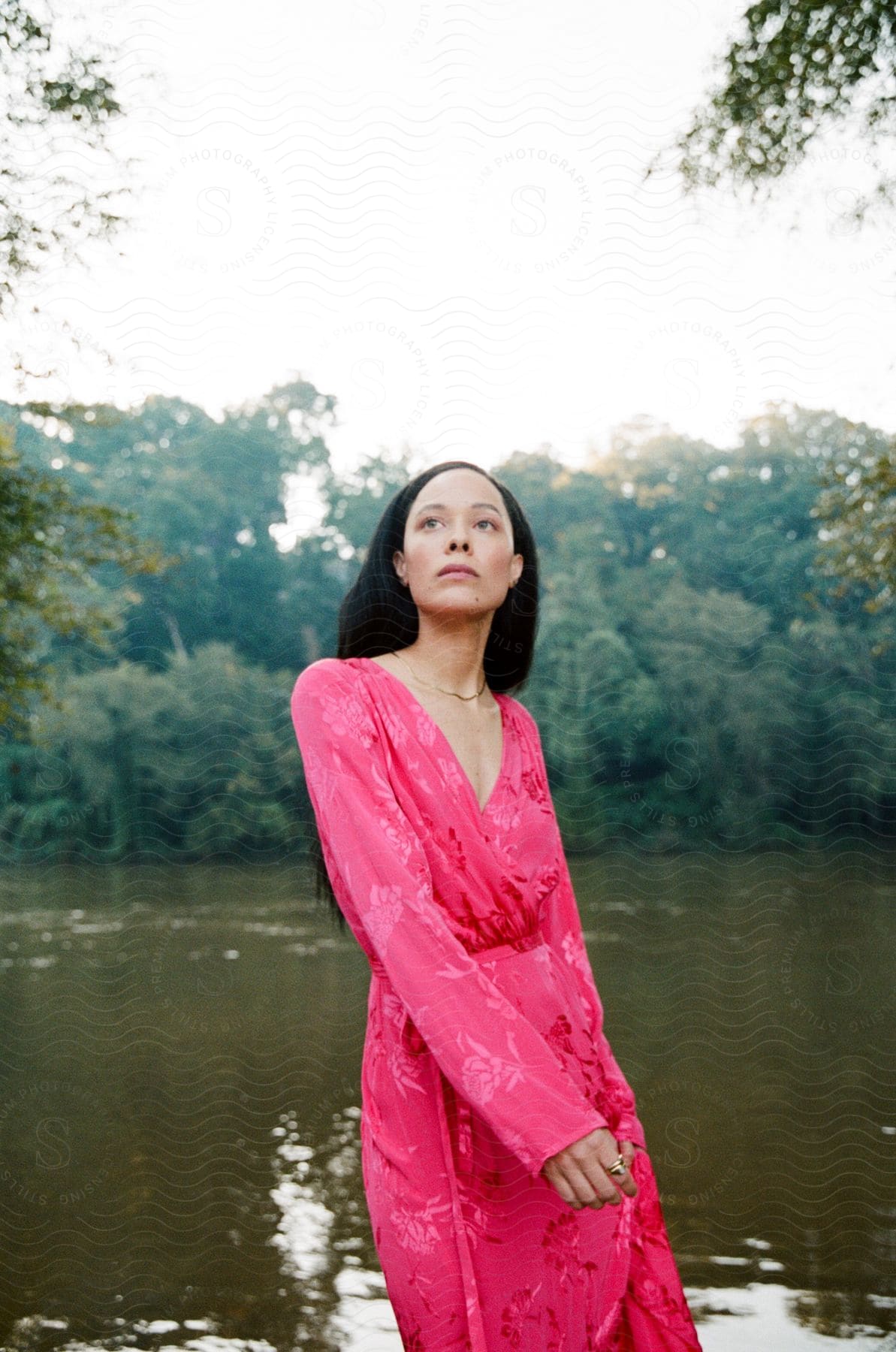 A woman modeling a robe outdoors near a lake.