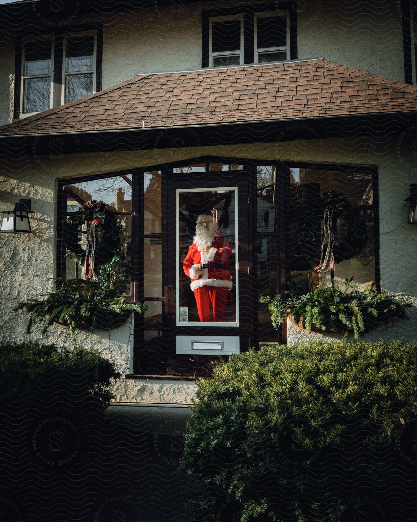 The front of a home decorated with a wreath and a full size santa claus decal on the front door