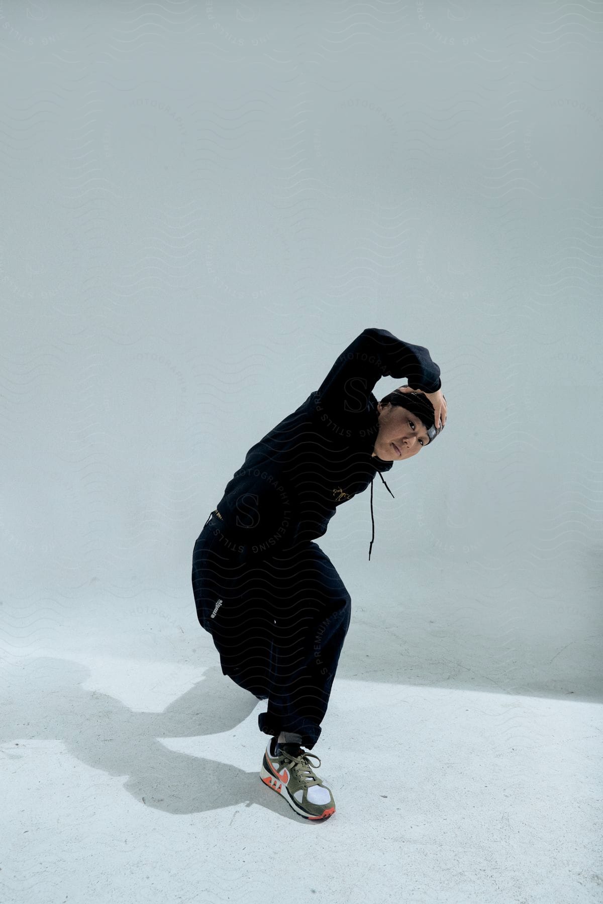 A young Asian man dressed in black winter attire strikes a pose amidst the snow.