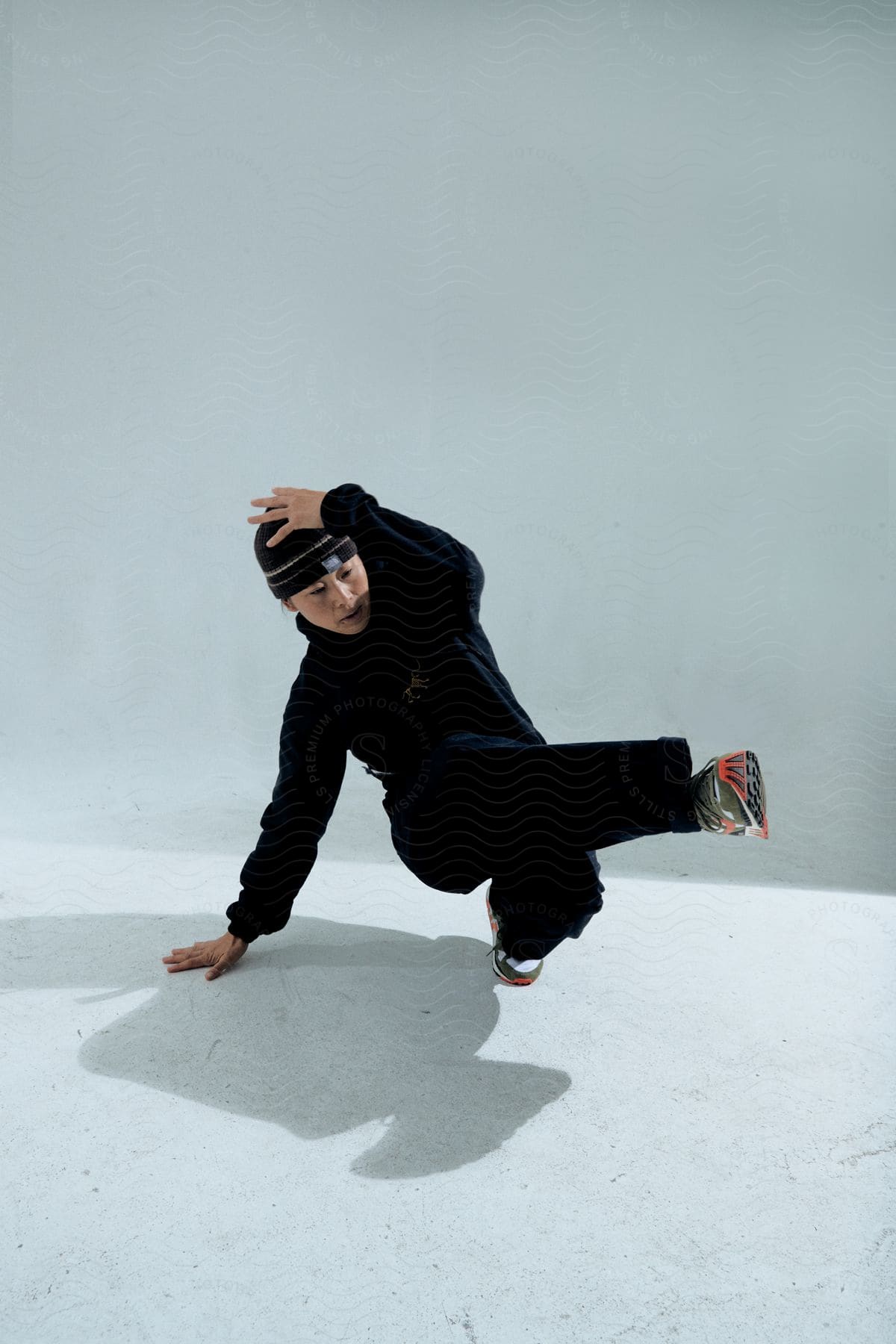 Stock photo of woman in a cap and sweatshirt dancing break dance.