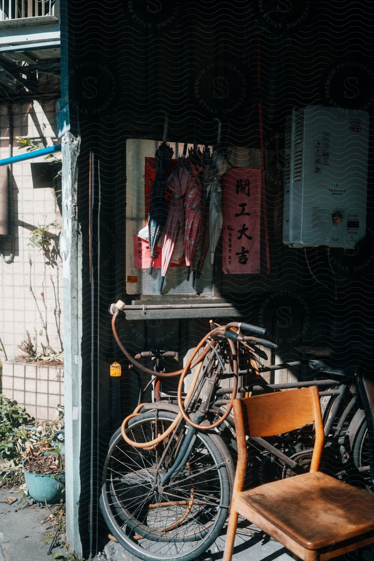 Umbrellas and bicycles amongst other items fill open garage on a sunny day.