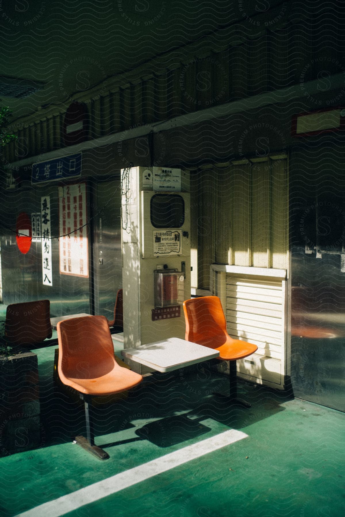 An interior of an establishment with two orange chairs and a small white table between them