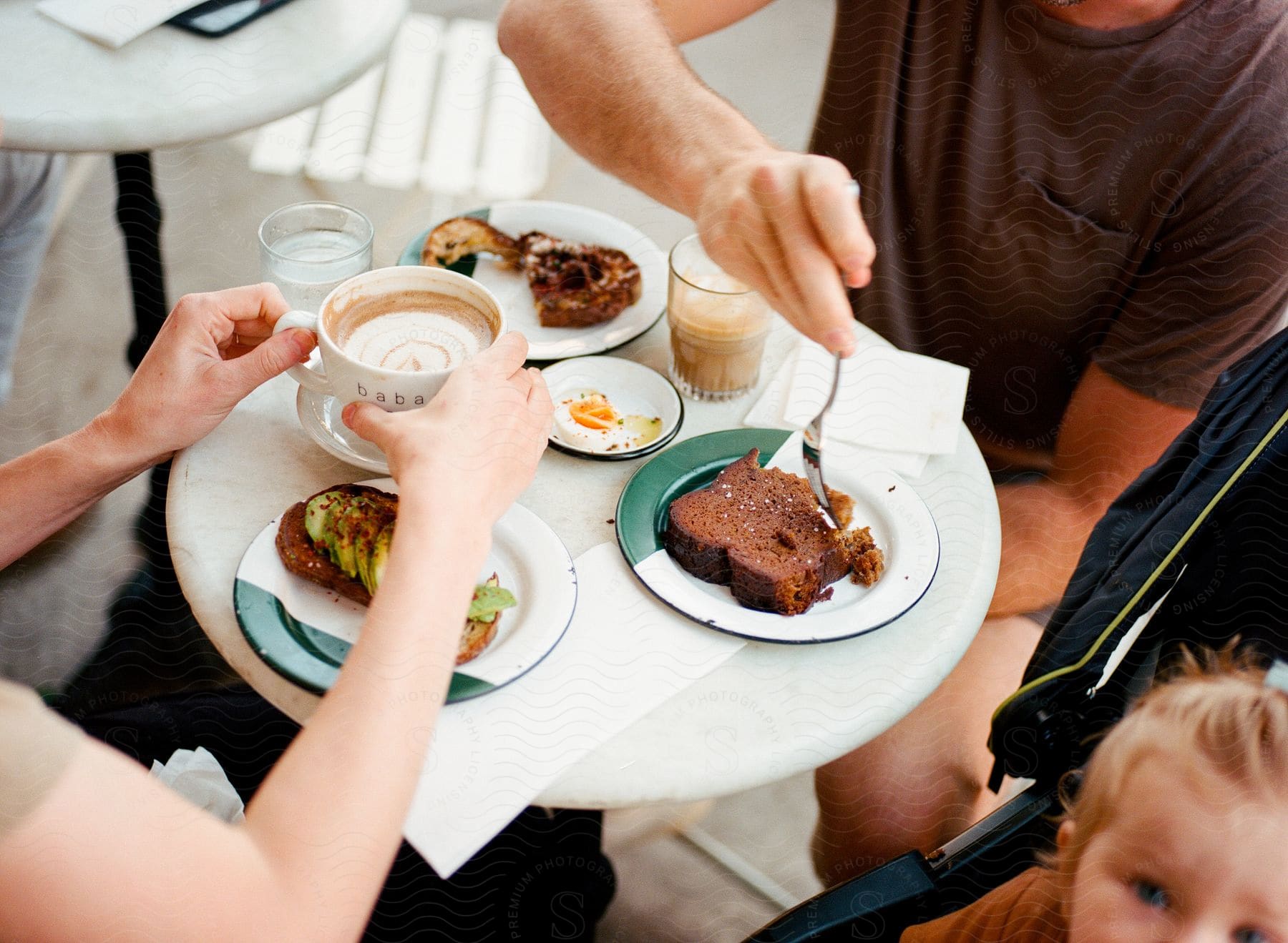 People are eating breakfast and drinking coffee at a small table.