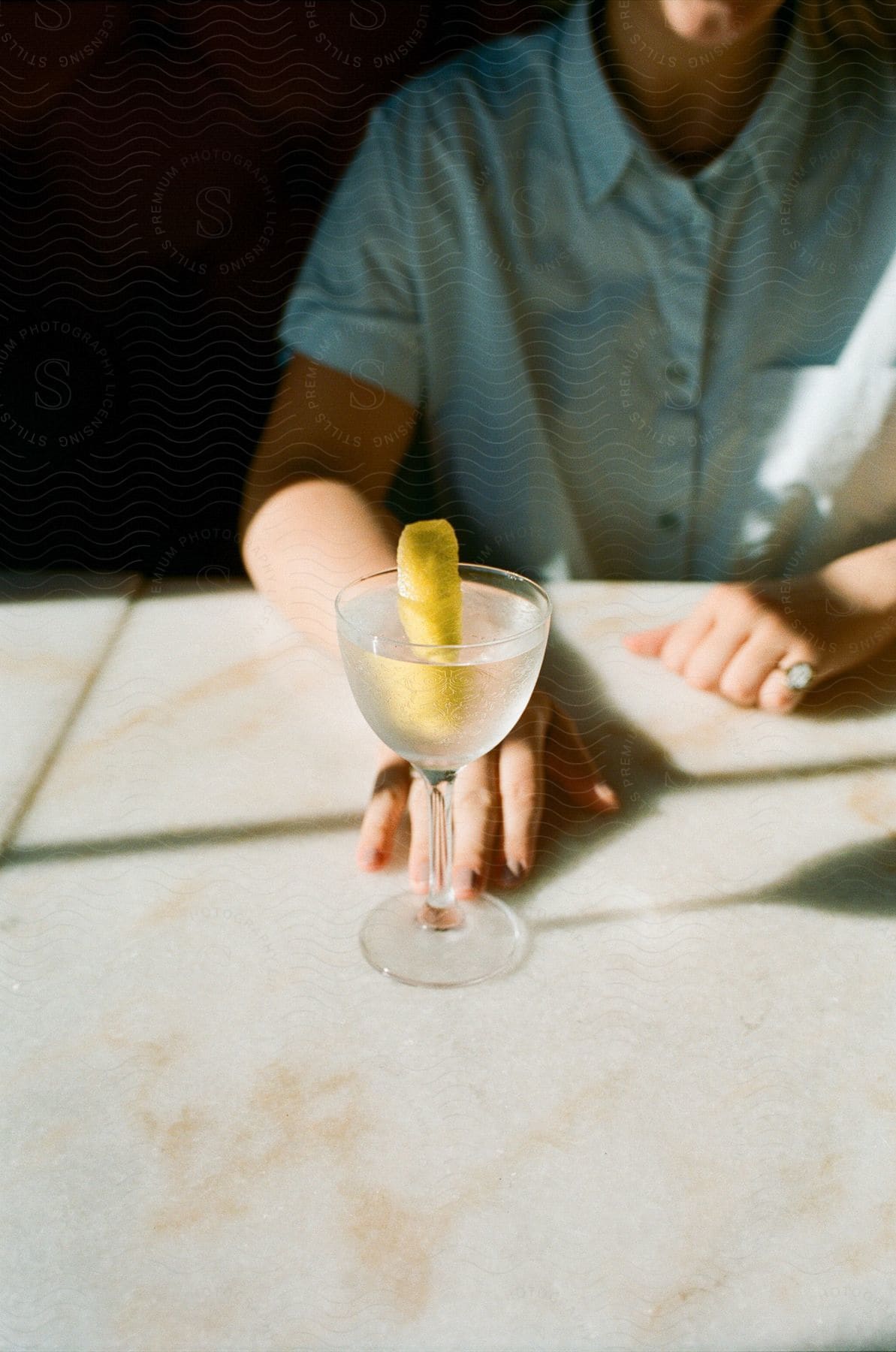 a person holding a glass of cocktail sitting behind a table