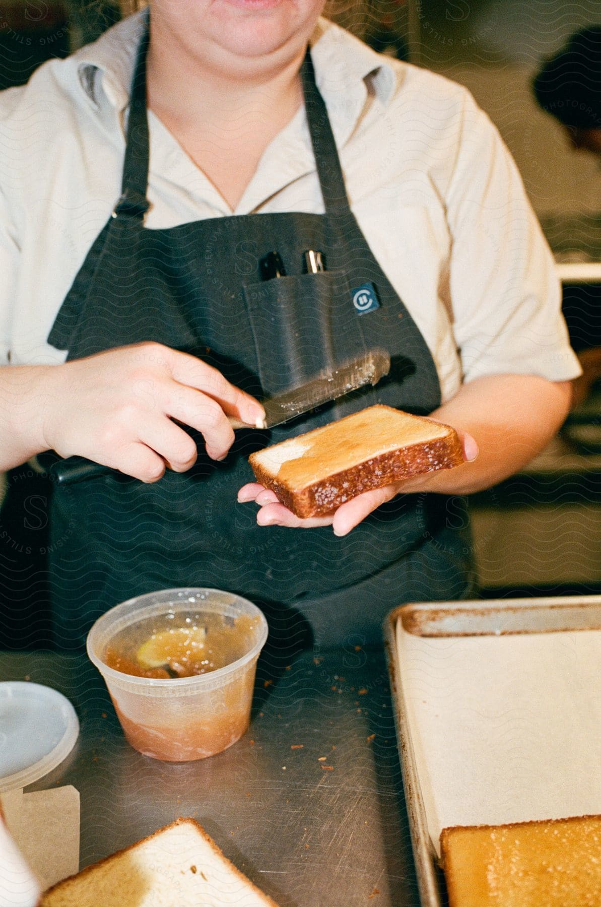 A person spreading a topping on a slice of bread.