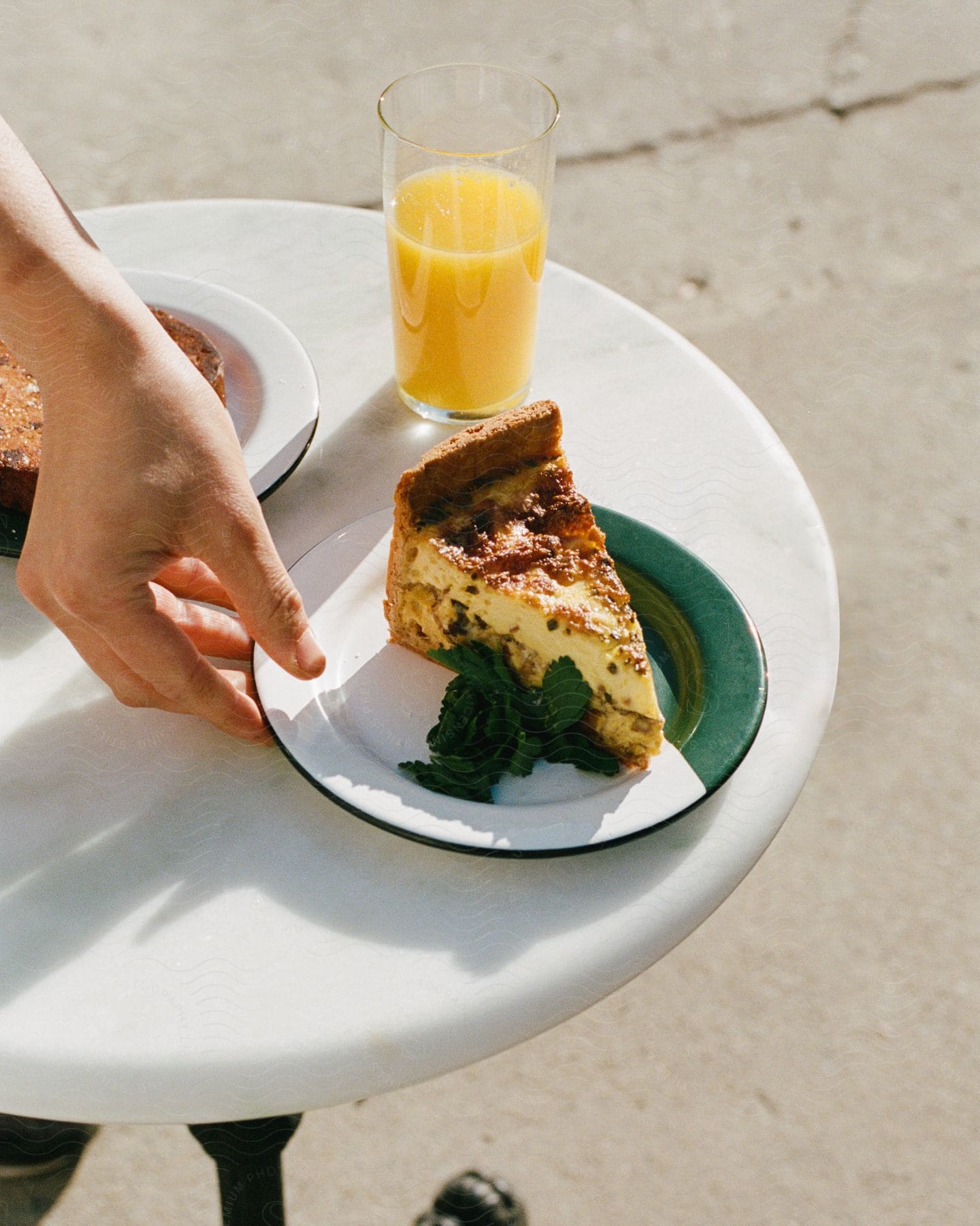 A piece of pie and a glass of juice on a white table outdoors.