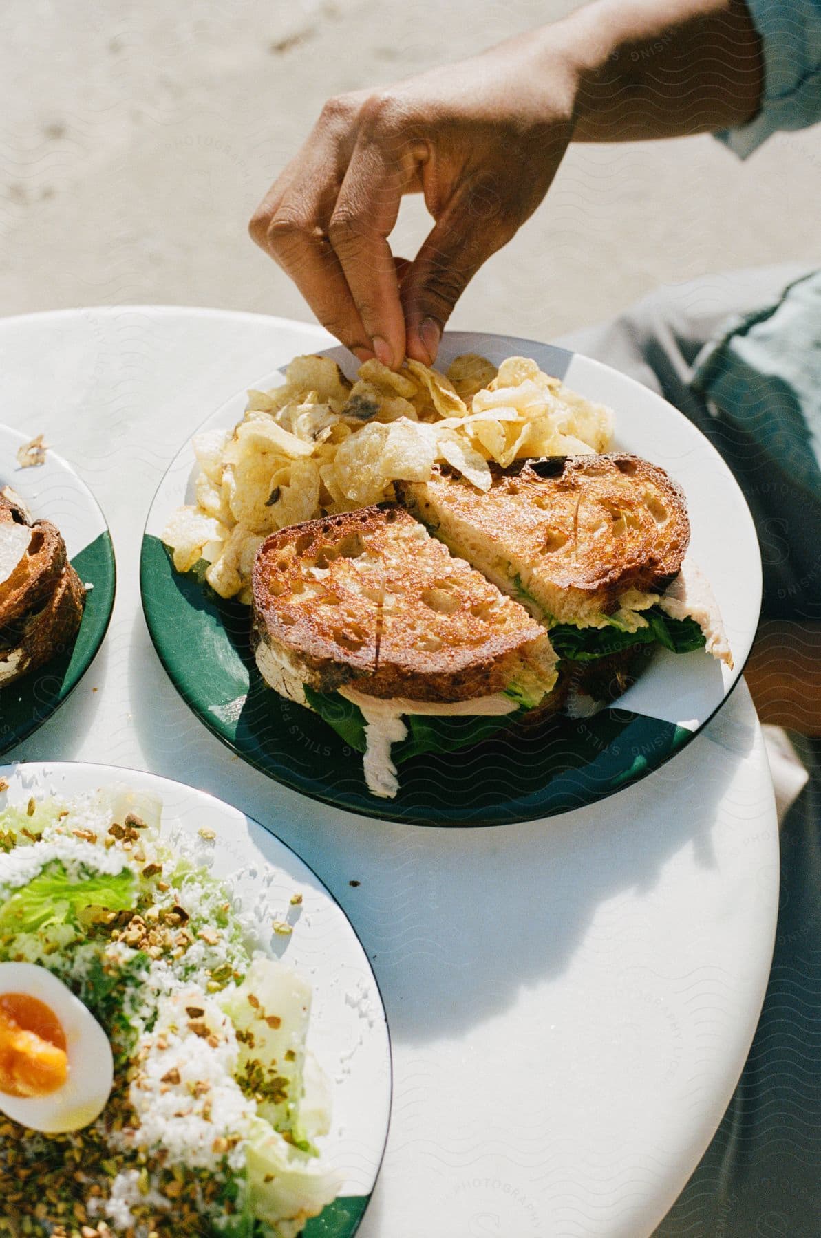 A person grabbing chips off a plate at a restaurant.