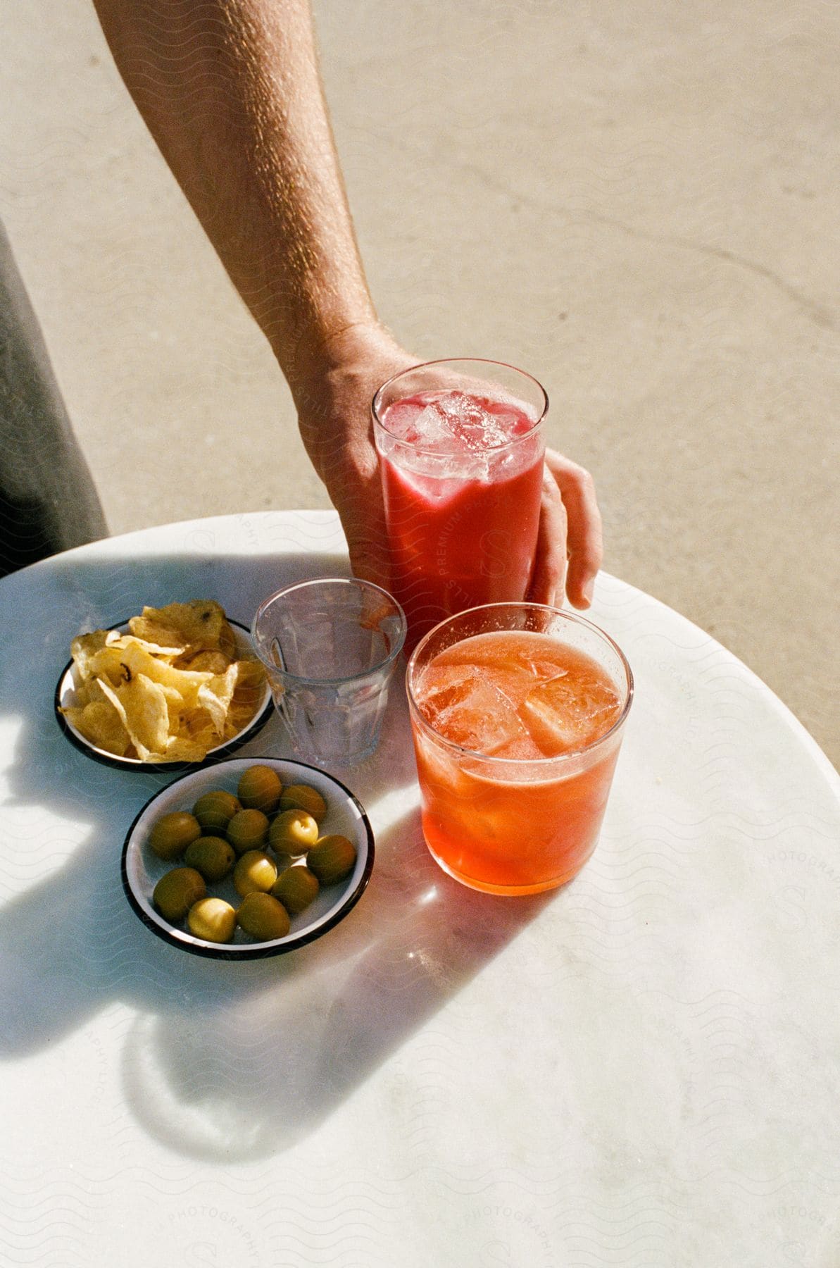 A person setting down some drinks at a table outdoors.