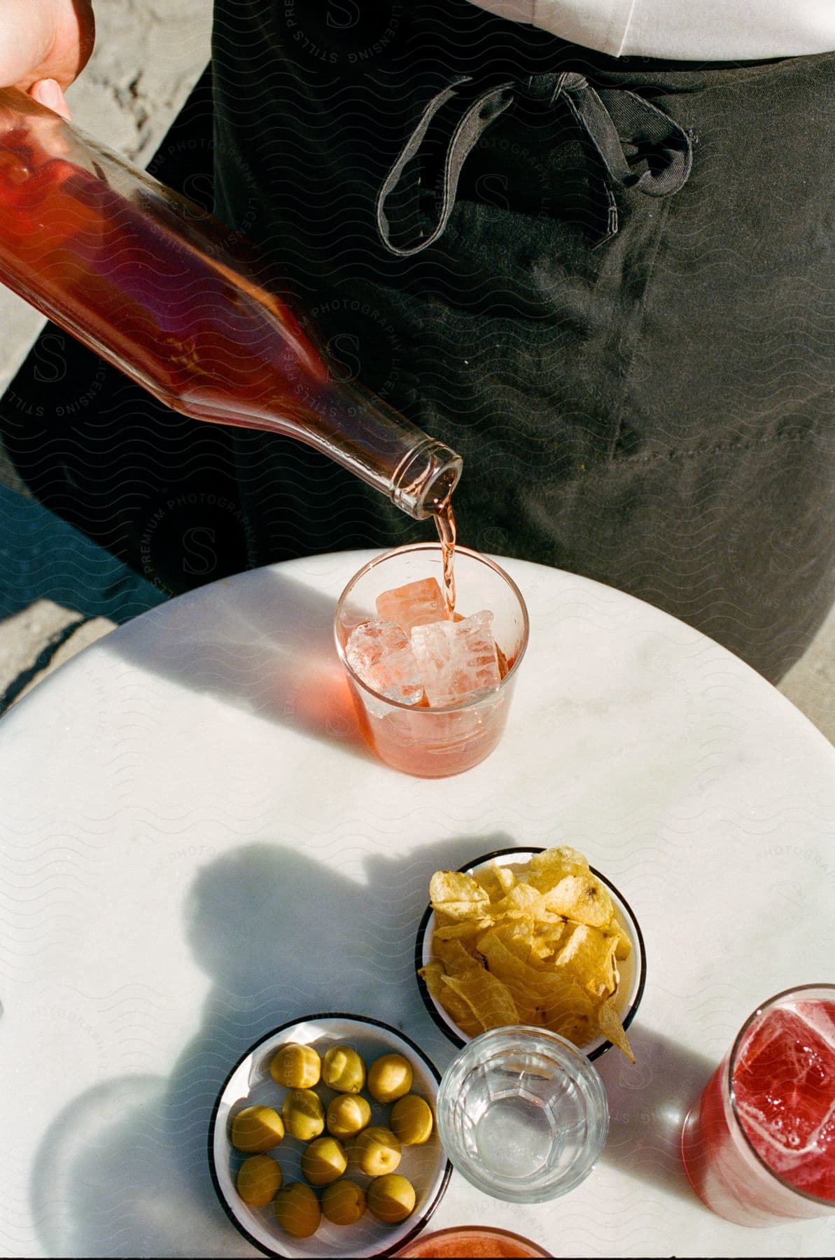 A person pouring alcohol into a glass at a table outdoors.