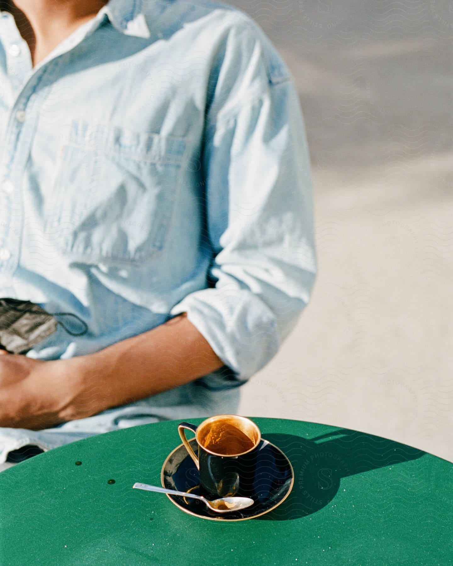 Woman sits at outdoor table with tea cup and saucer.