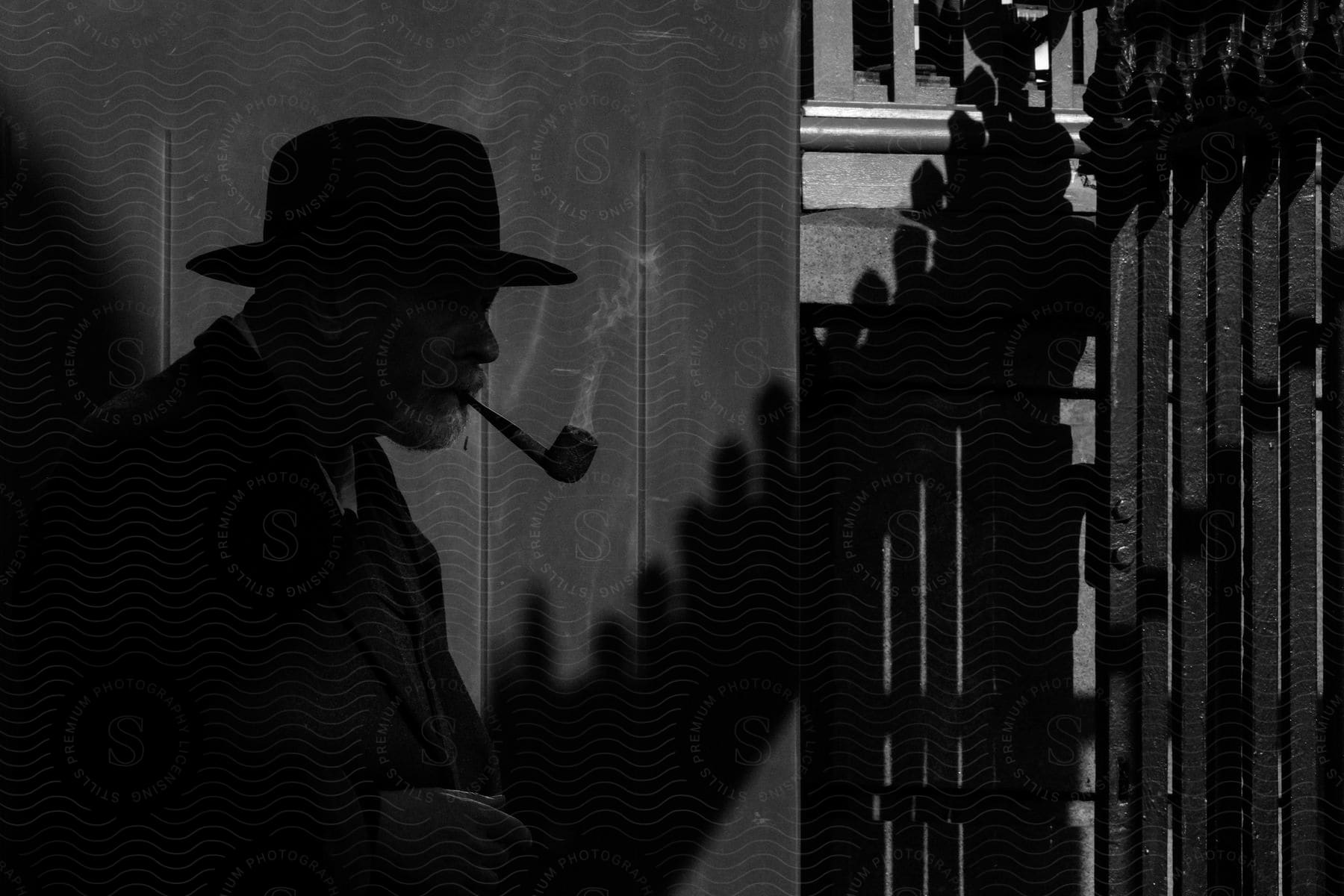 A silhouette of a man smoking a pipe outdoors.