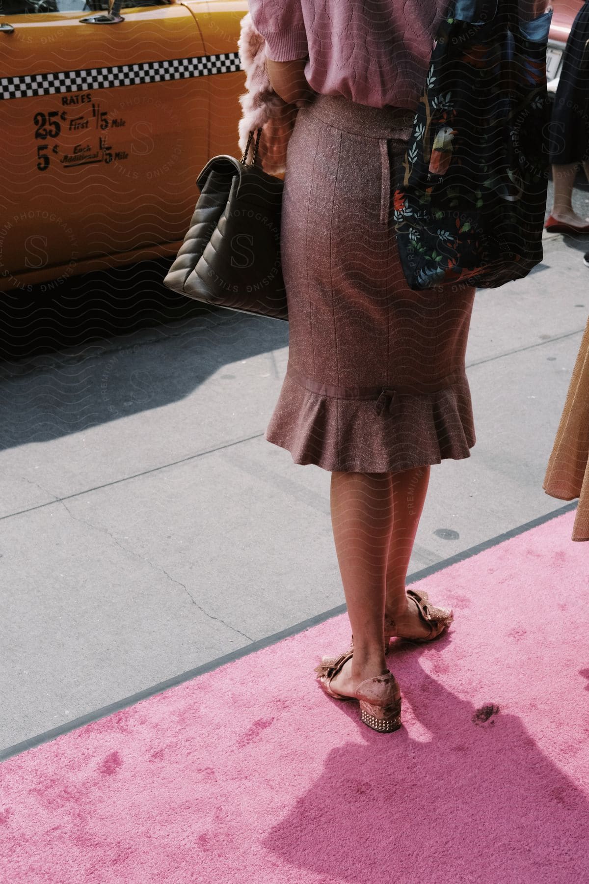 A person is wearing designer clothes and is stepping on a pink carpet