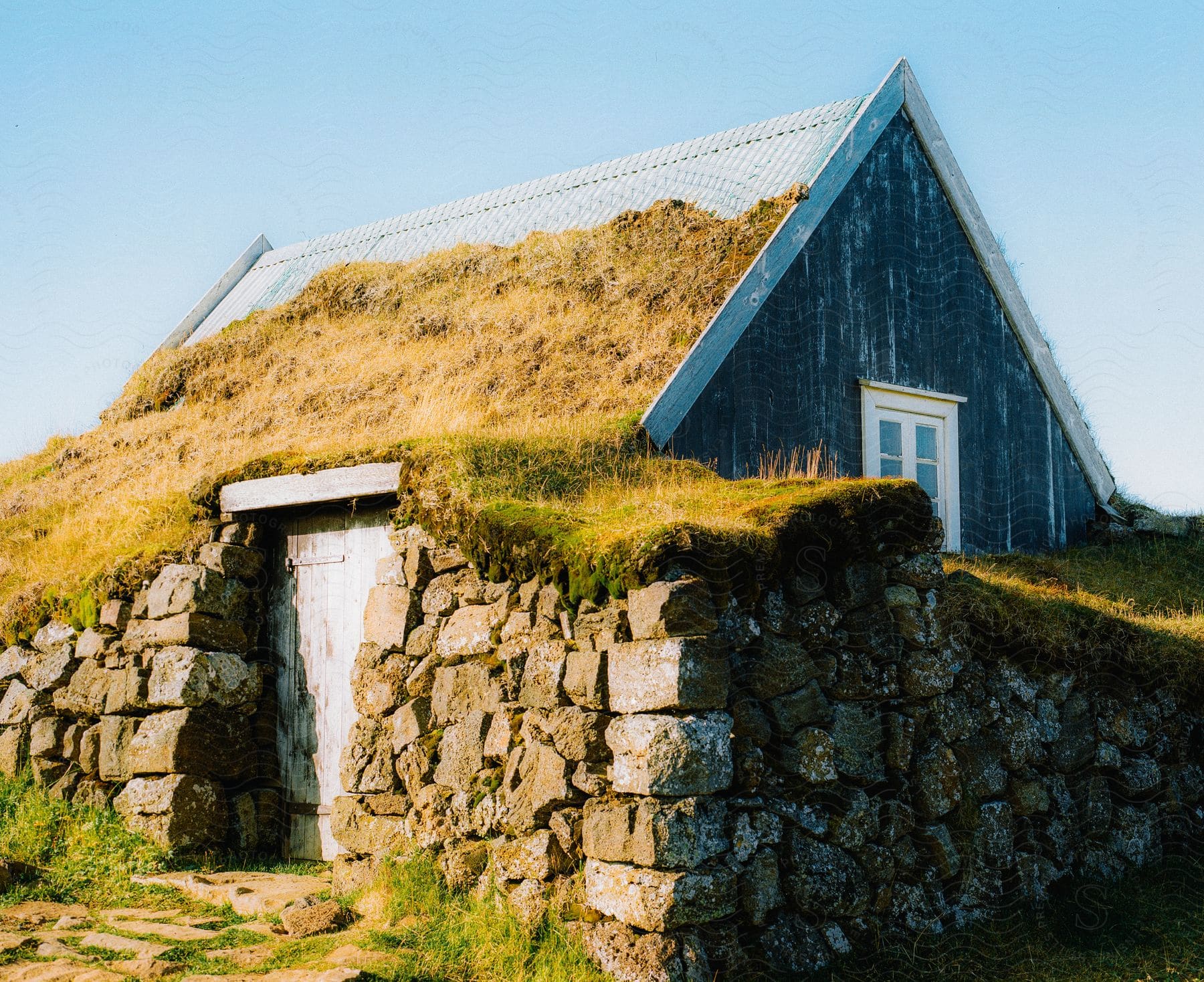 A small hut made of wood, stones and grass during the sunny morning.