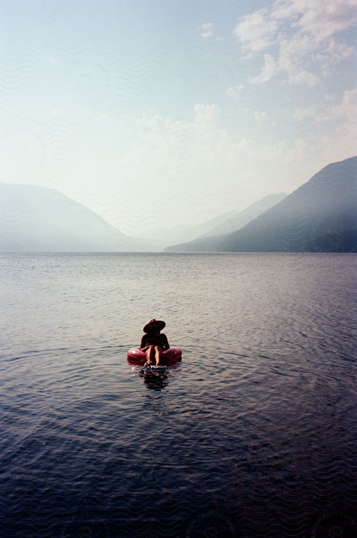 A person in a pink buoy on the beach during a hot summer day.