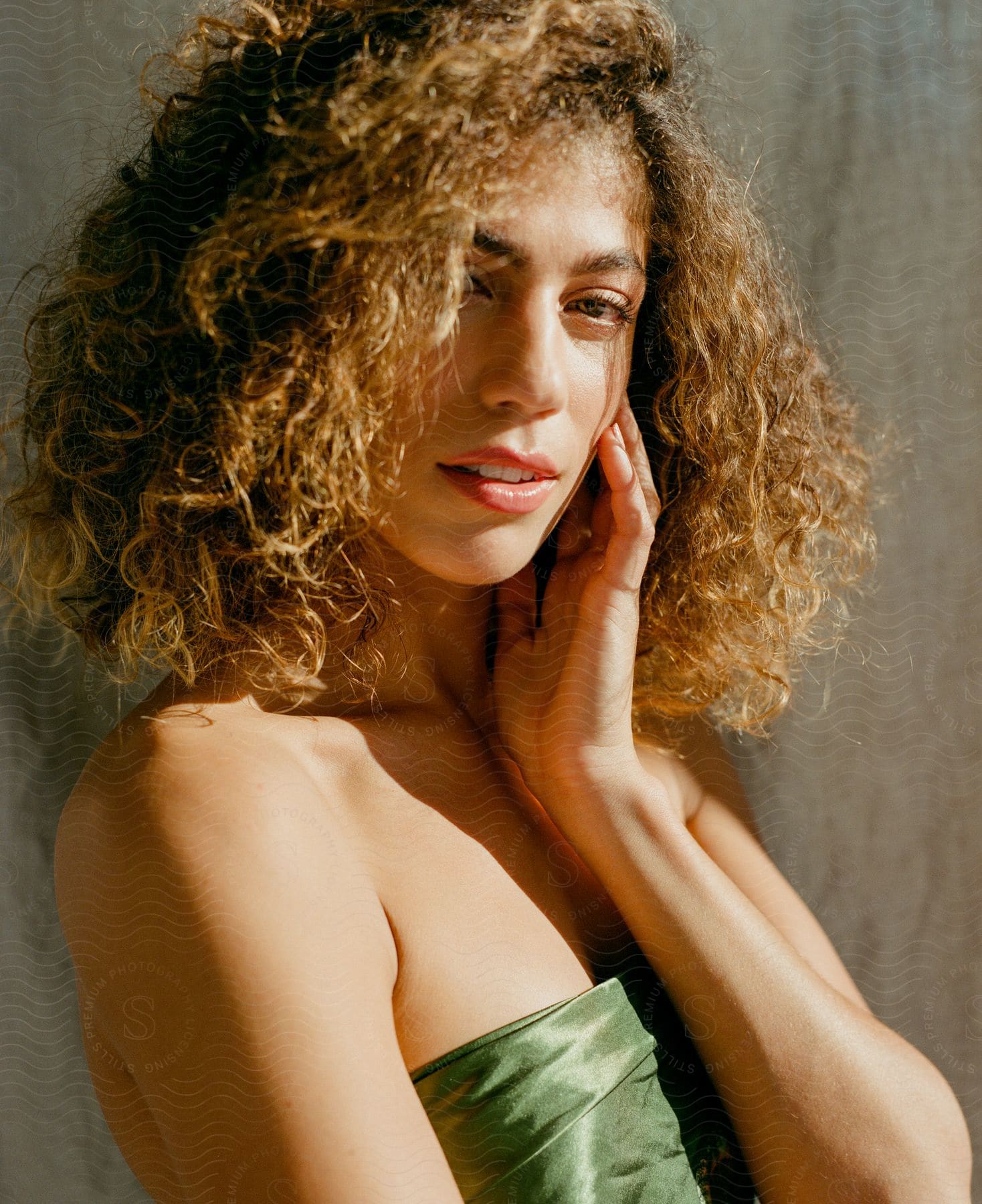 Portrait of a young woman with one hand under her face and curly hair.