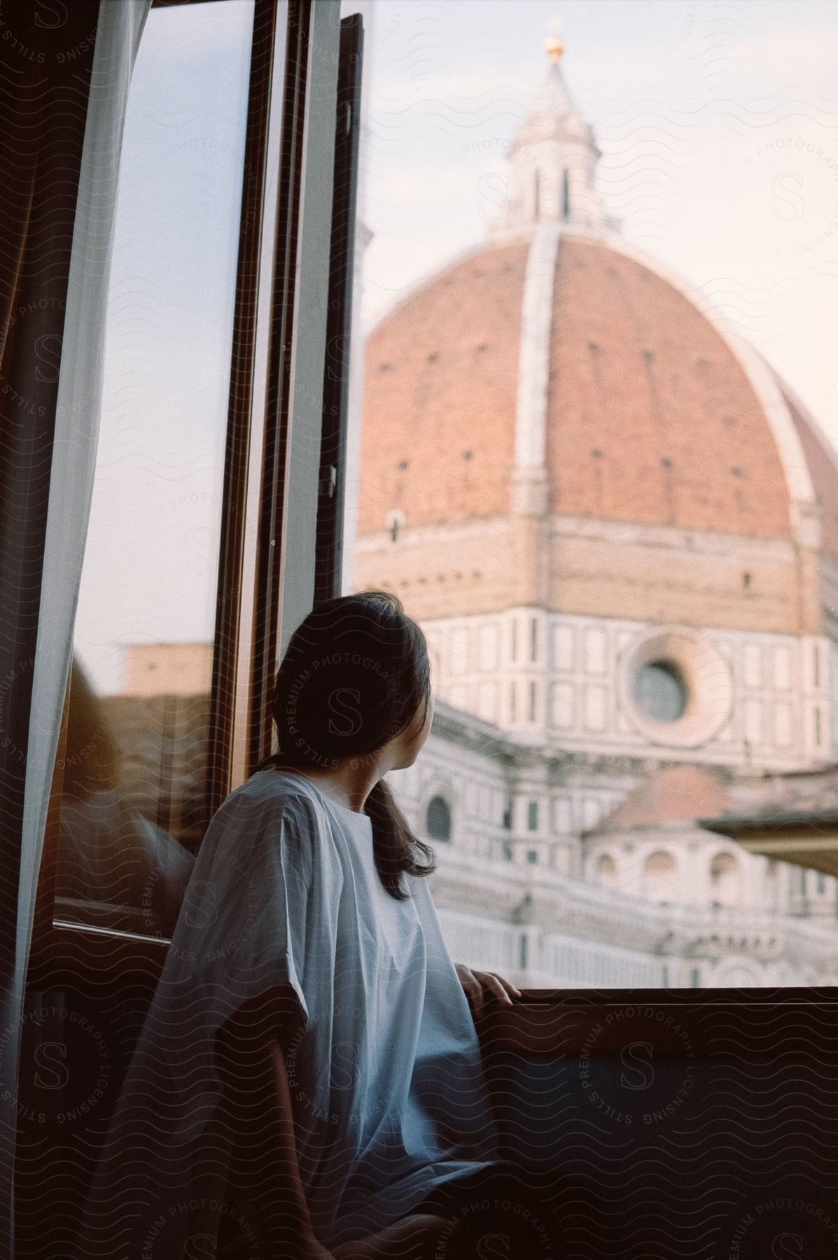 A person admiring the cathedral through the window of their house.