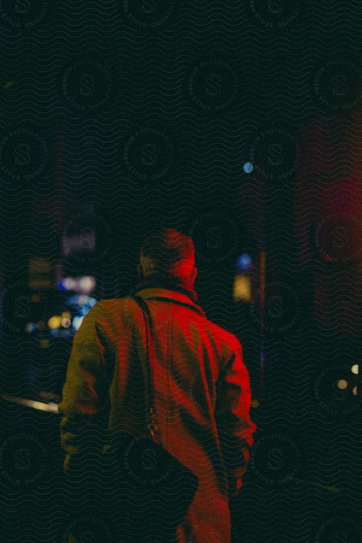 A man walks on a downtown street at night with a bag over his shoulder