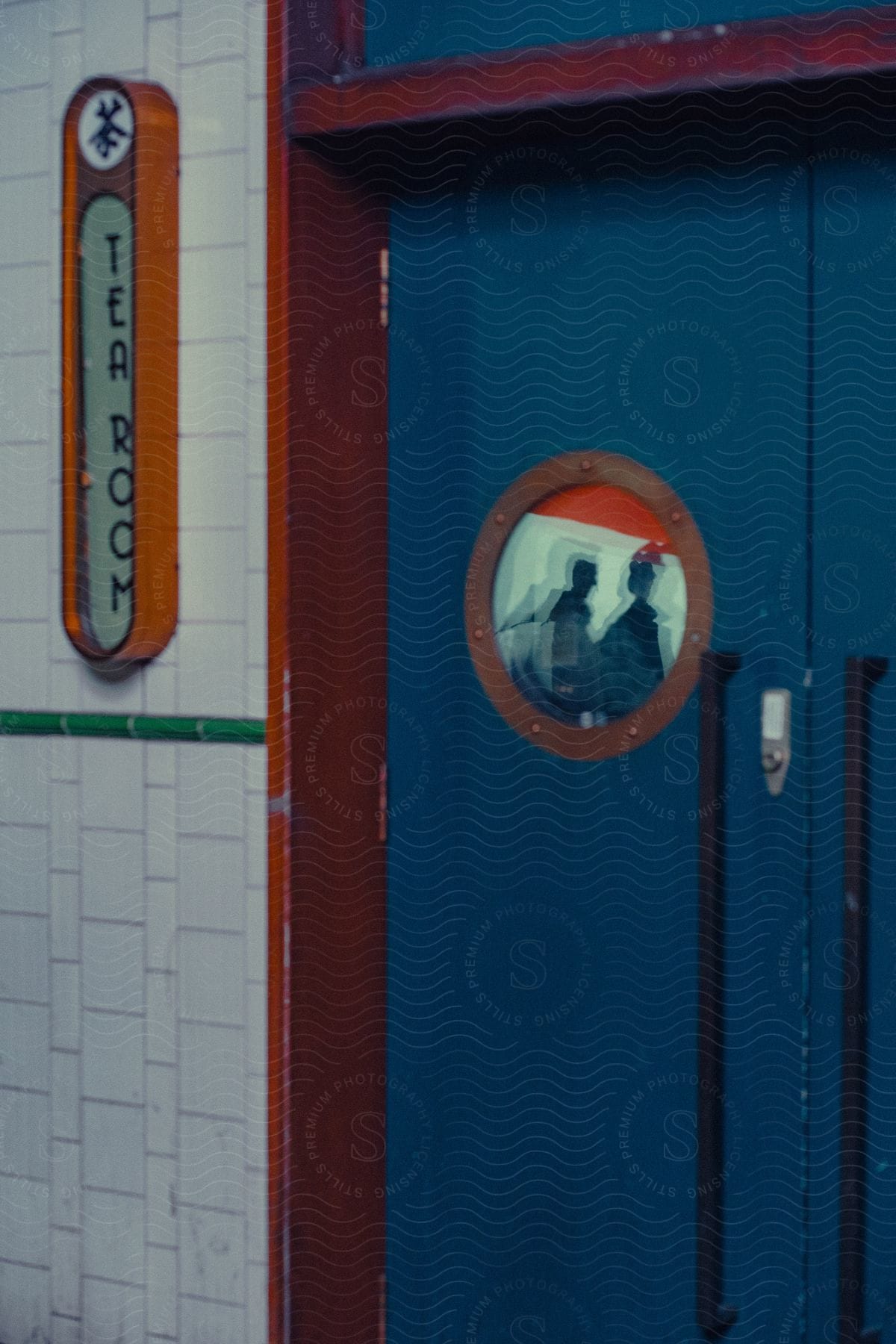 Vertical Tea Room sign sits on the white-tiled wall to the left of a blue door set in a red frame with chipped paint.