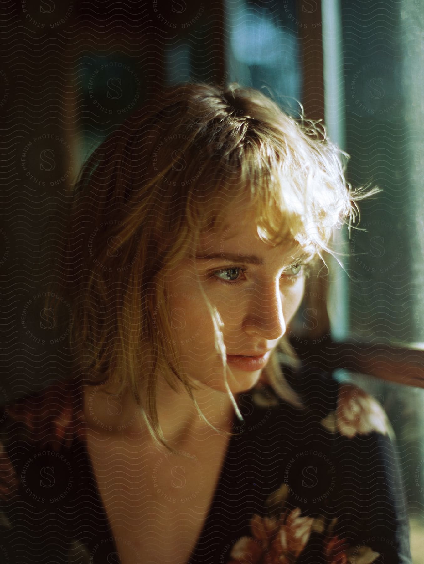 A woman looks ahead as she sits near windows