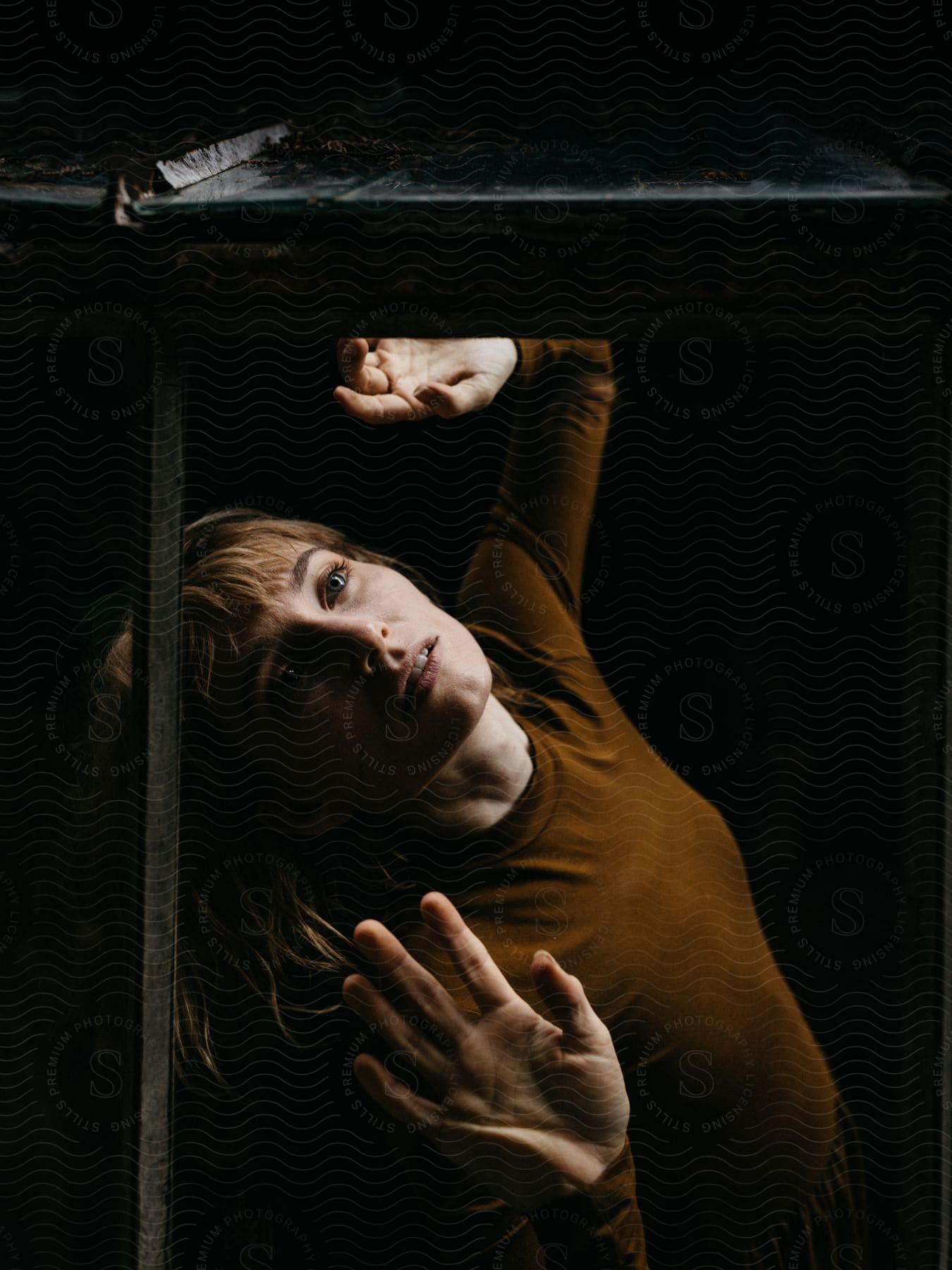 Portrait of a woman in a dark, mirrored room with an unusual facial expression.
