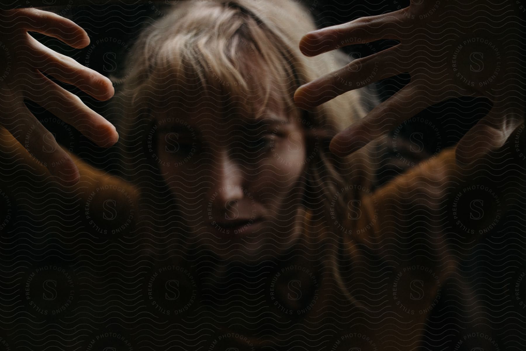 Stock photo of a woman is dancing in a dark room with her hands over her head