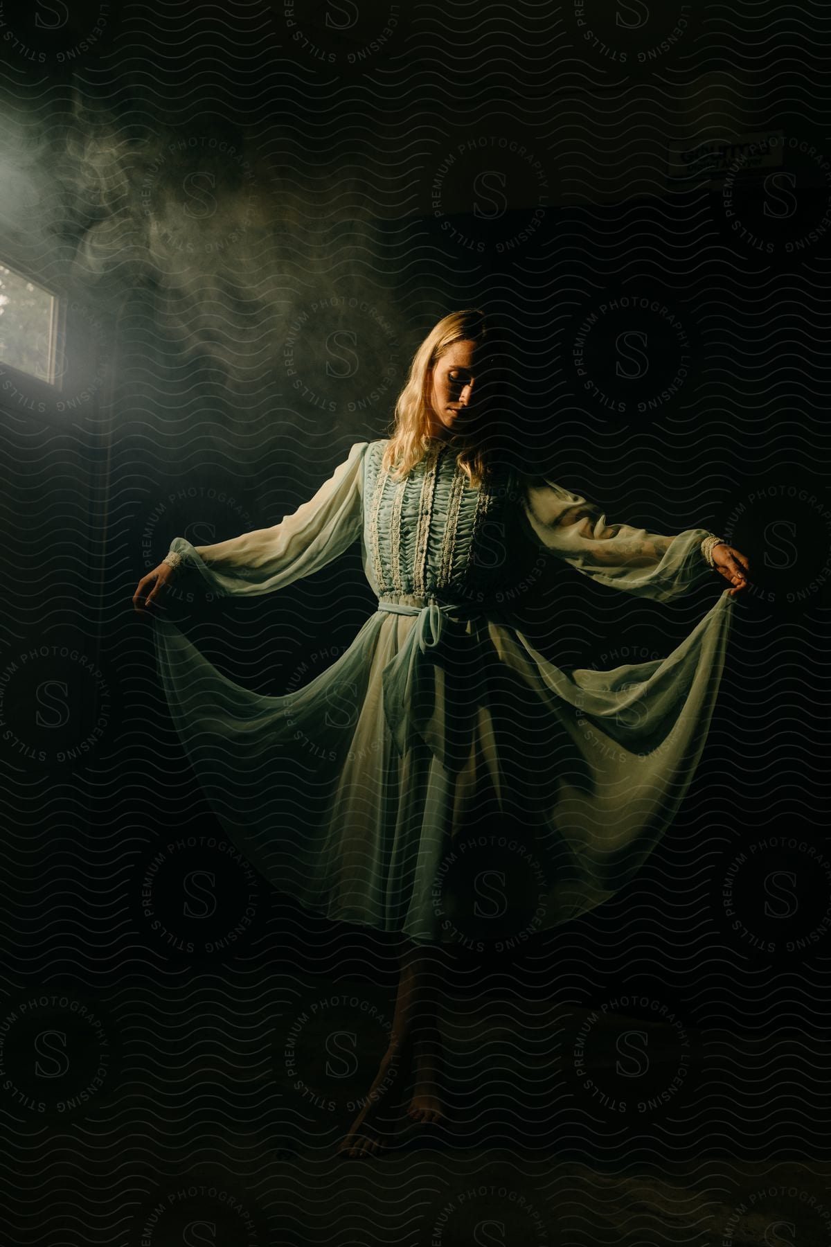 A woman in a vintage or historical style dress standing in a misty room with light streaming in through a window