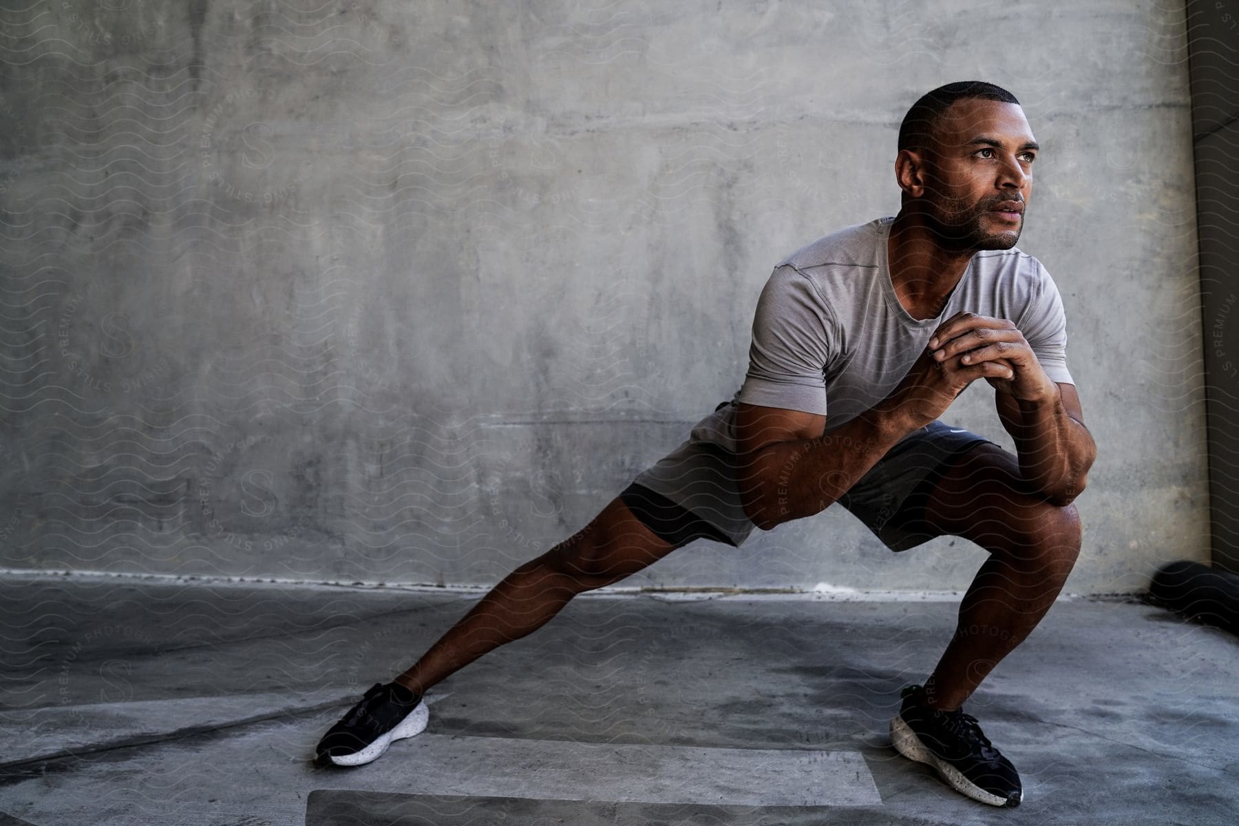 A man is standing near a wall doing stretching exercises