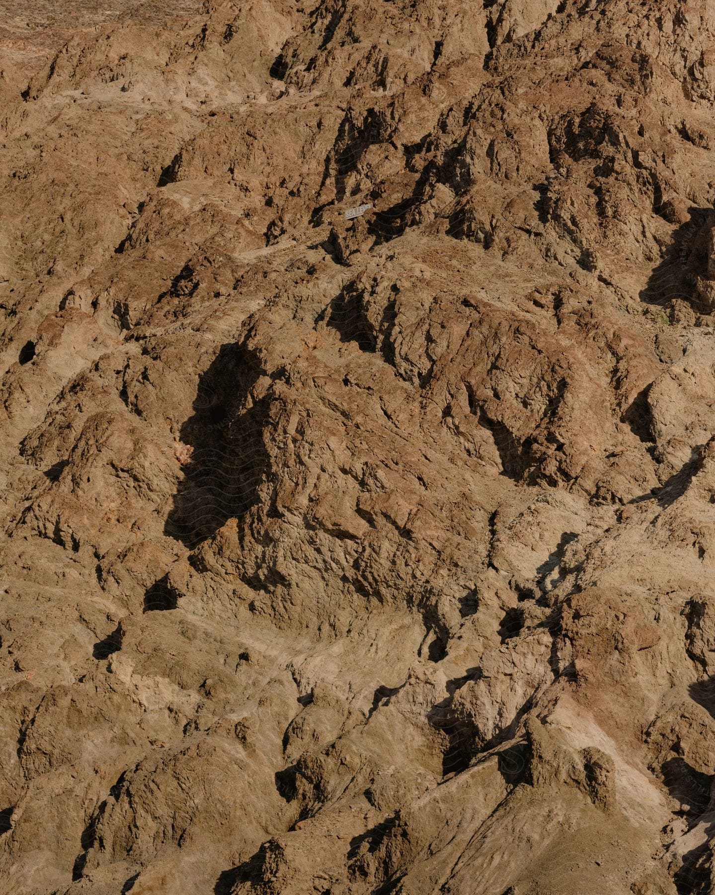 Aerial view of rugged brown mountain terrain with textured rock formations.