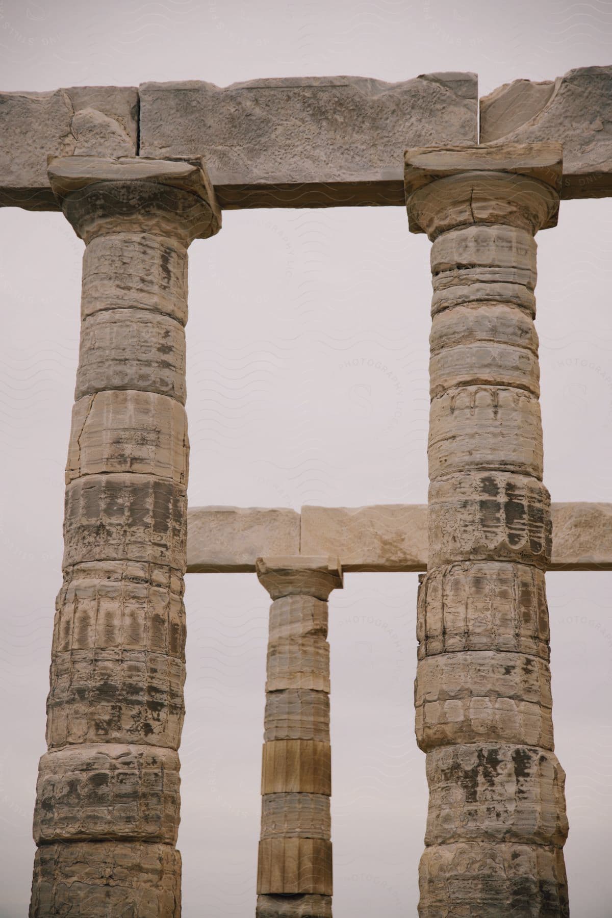 View of the columns of Cape Sounion, an archaeological site, on a cloudy day.