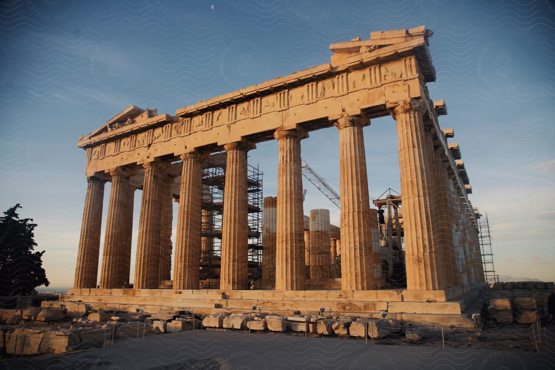 Columns hold up the ancient ruins of the Parthenon as construction scaffolds and a crane stand in the distance