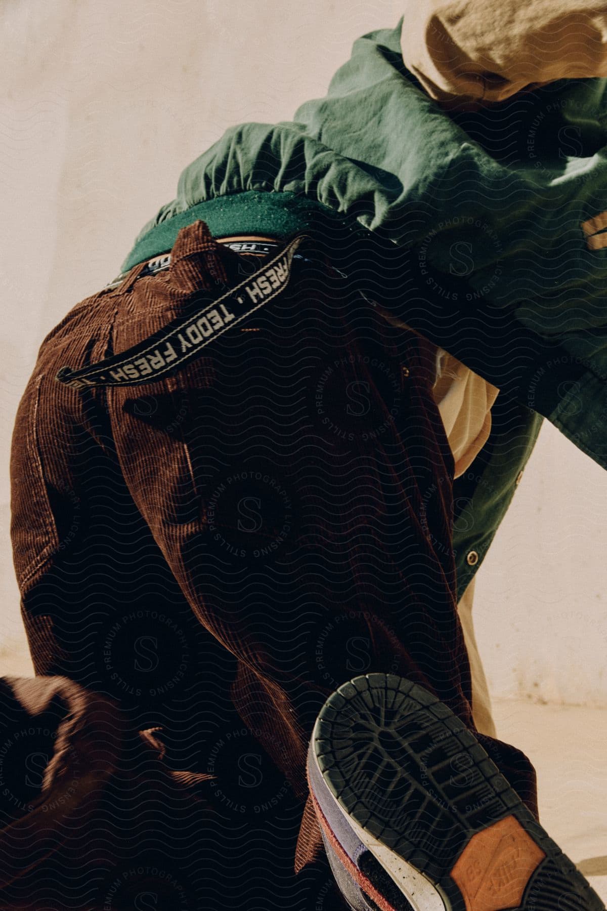 Close-up Of A Model's Legs Wearing Brown Twill Pants And A Bomber Jacket