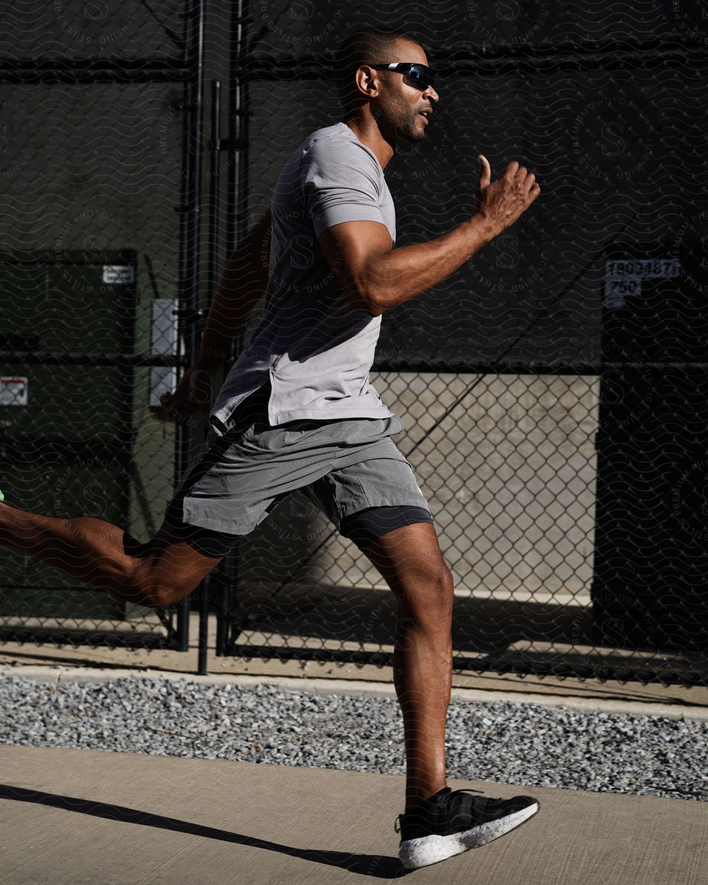 A man in grey athletic clothes running on a city sidewalk.