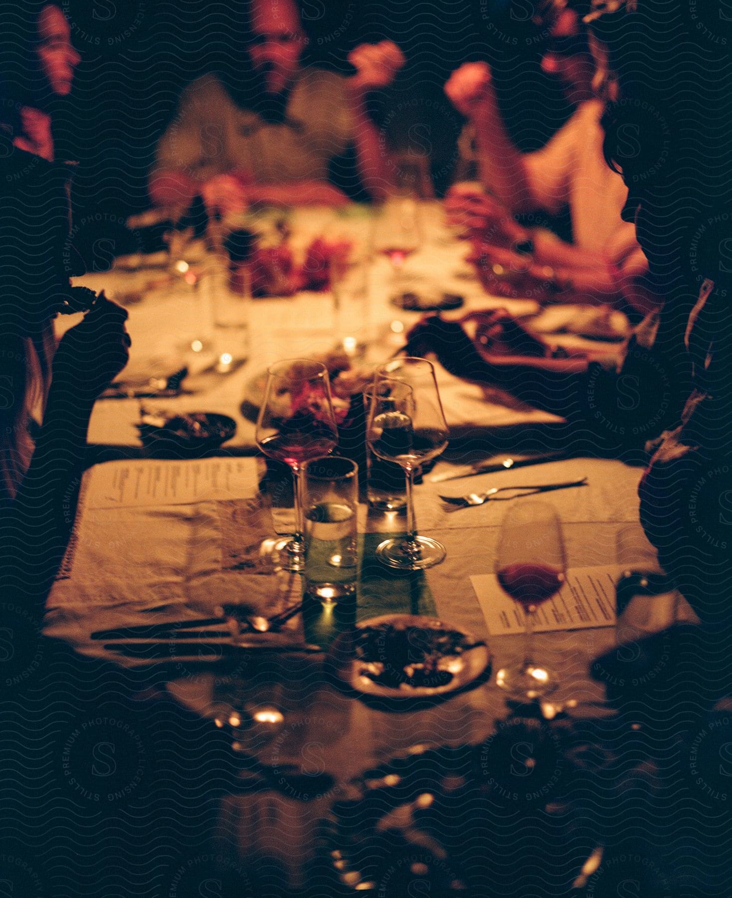 People sitting around a table, eating and drinking wine.