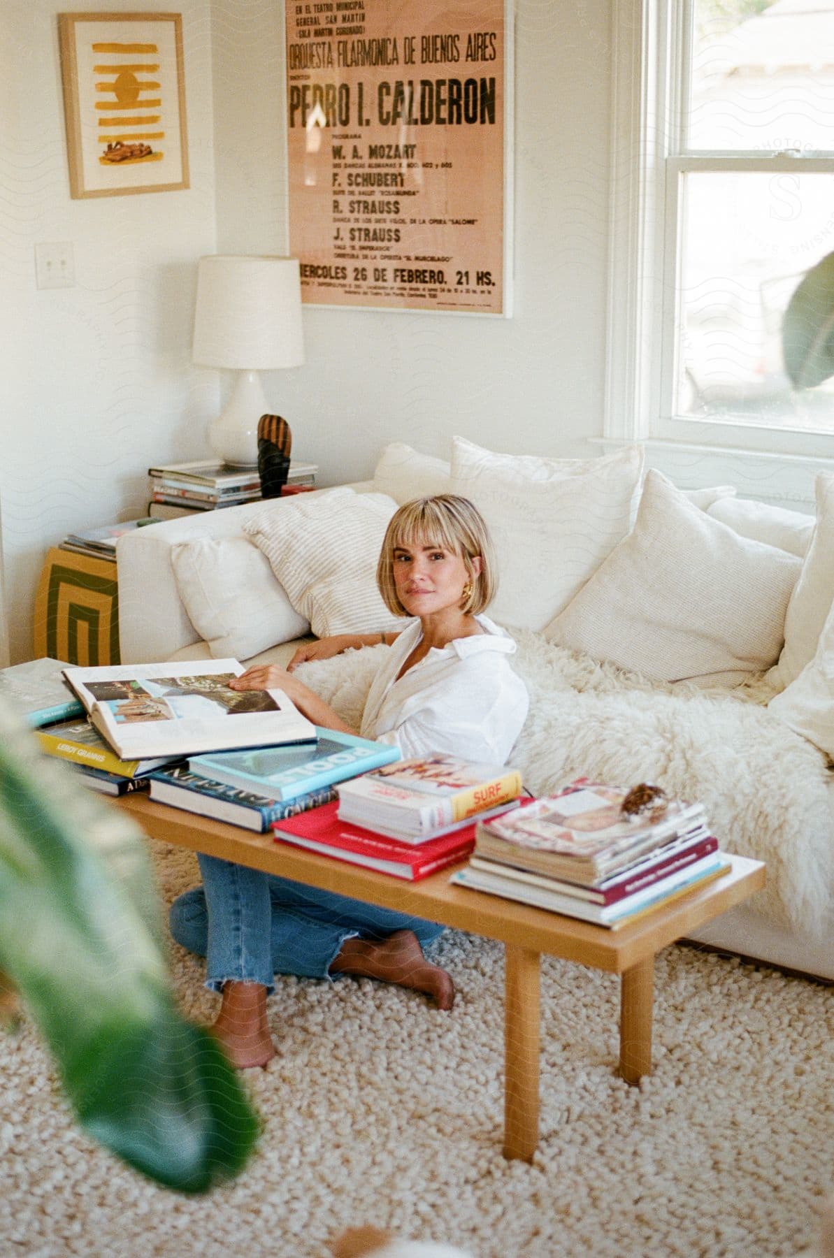 A woman sitting on her living room floor posed as if going through a coffee table book