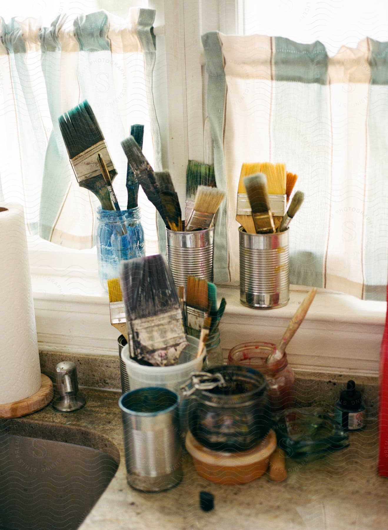 paint brushes are placed in cans and tin close to the window