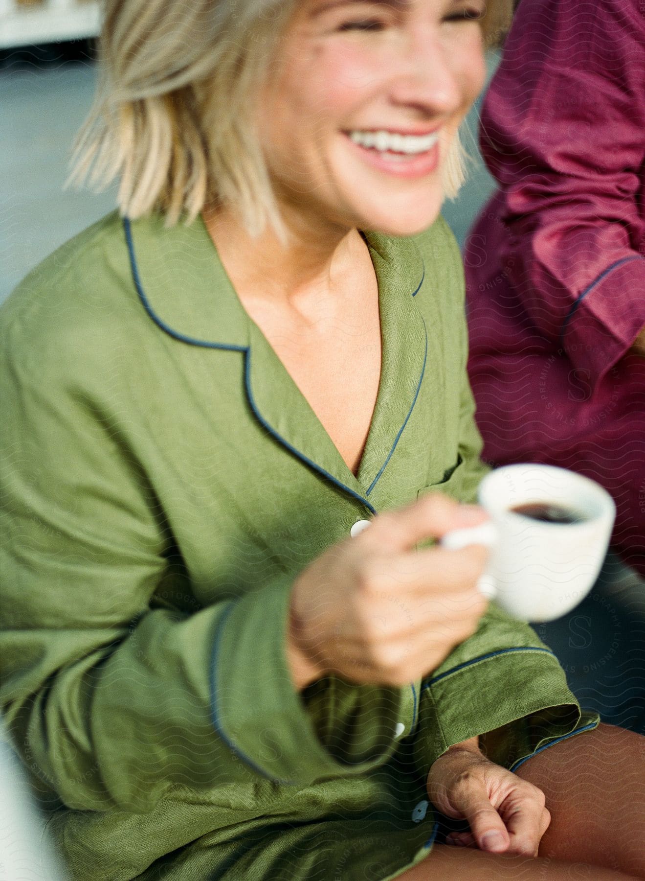 Smiling woman holding a cup and wearing a green outfit with blue details.