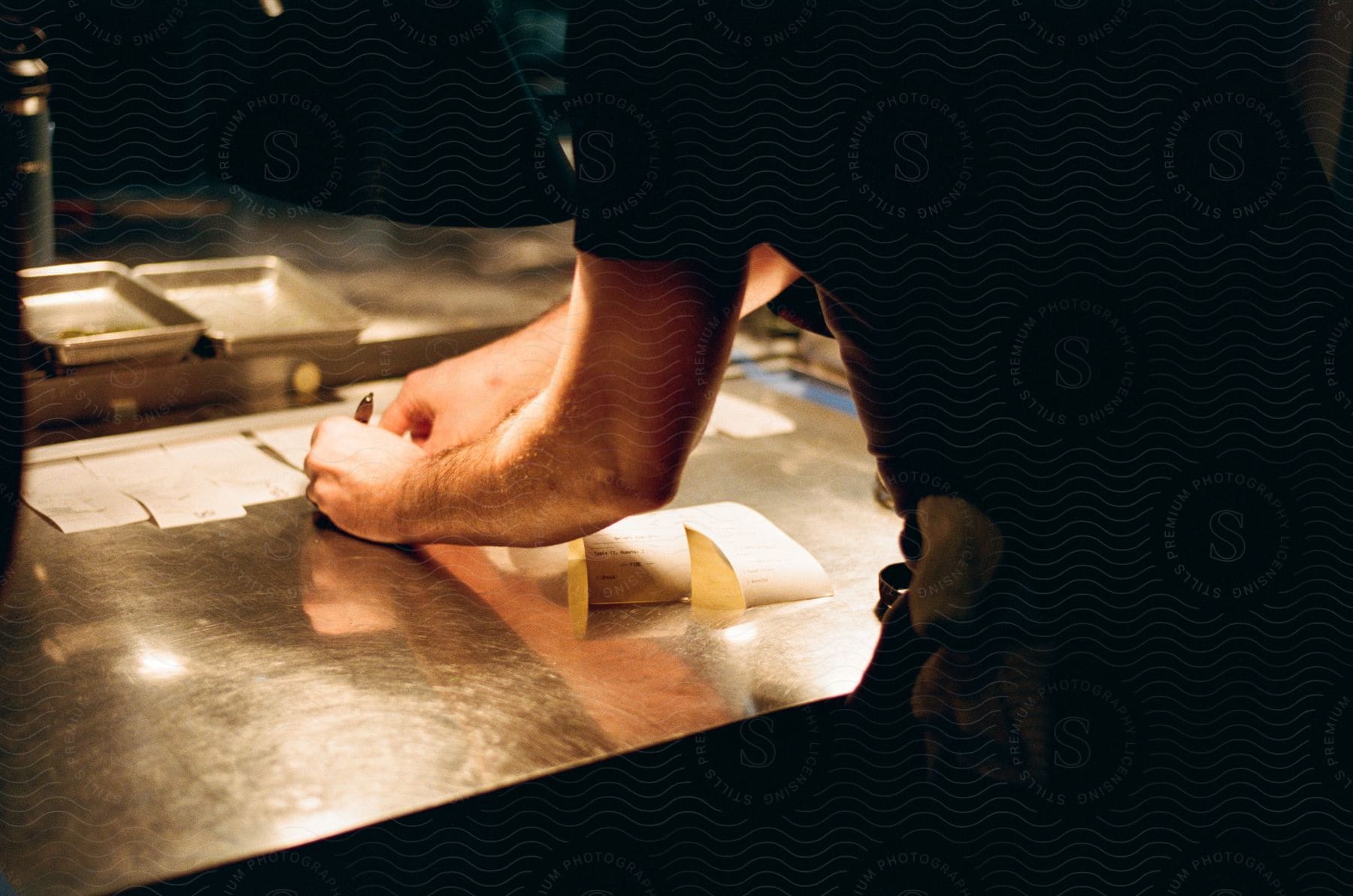 A man is leaning over a counter writing on receipts