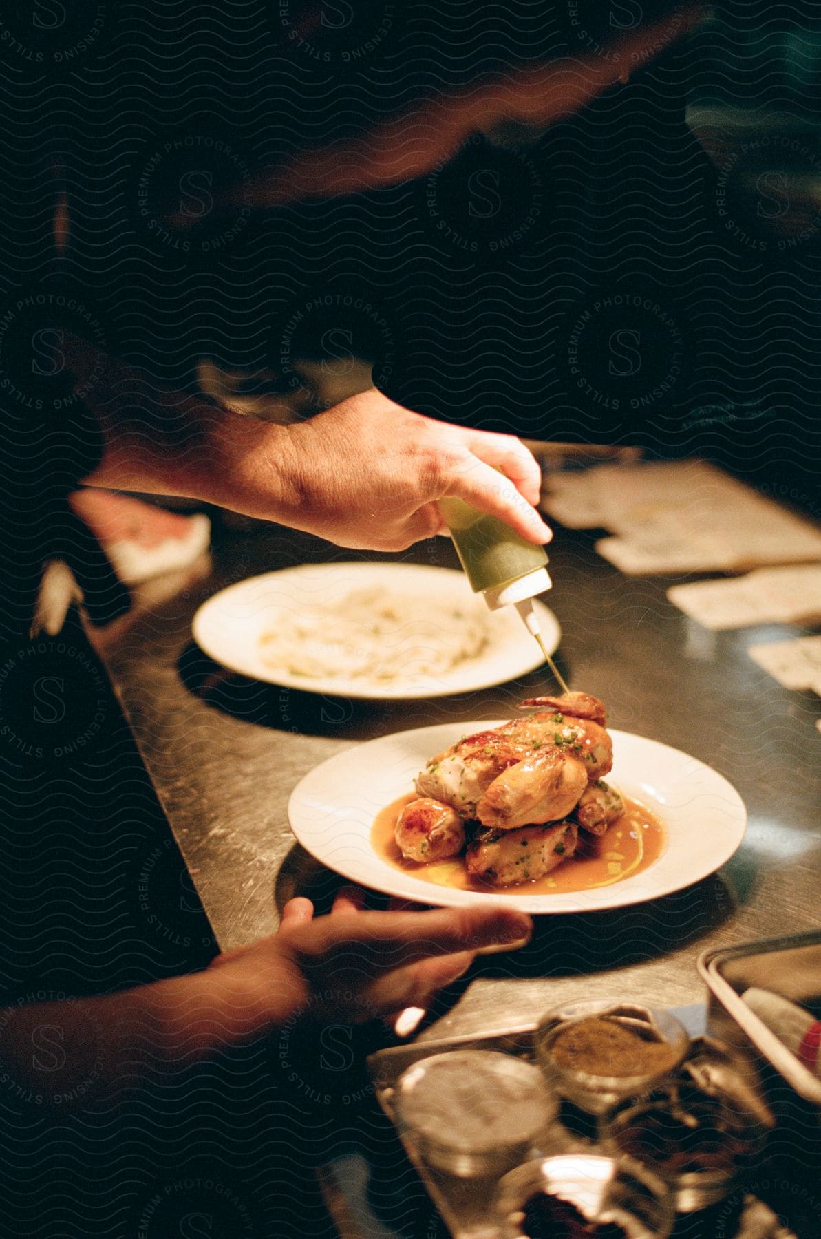 a person serving a meal by pouring a source on the chicken