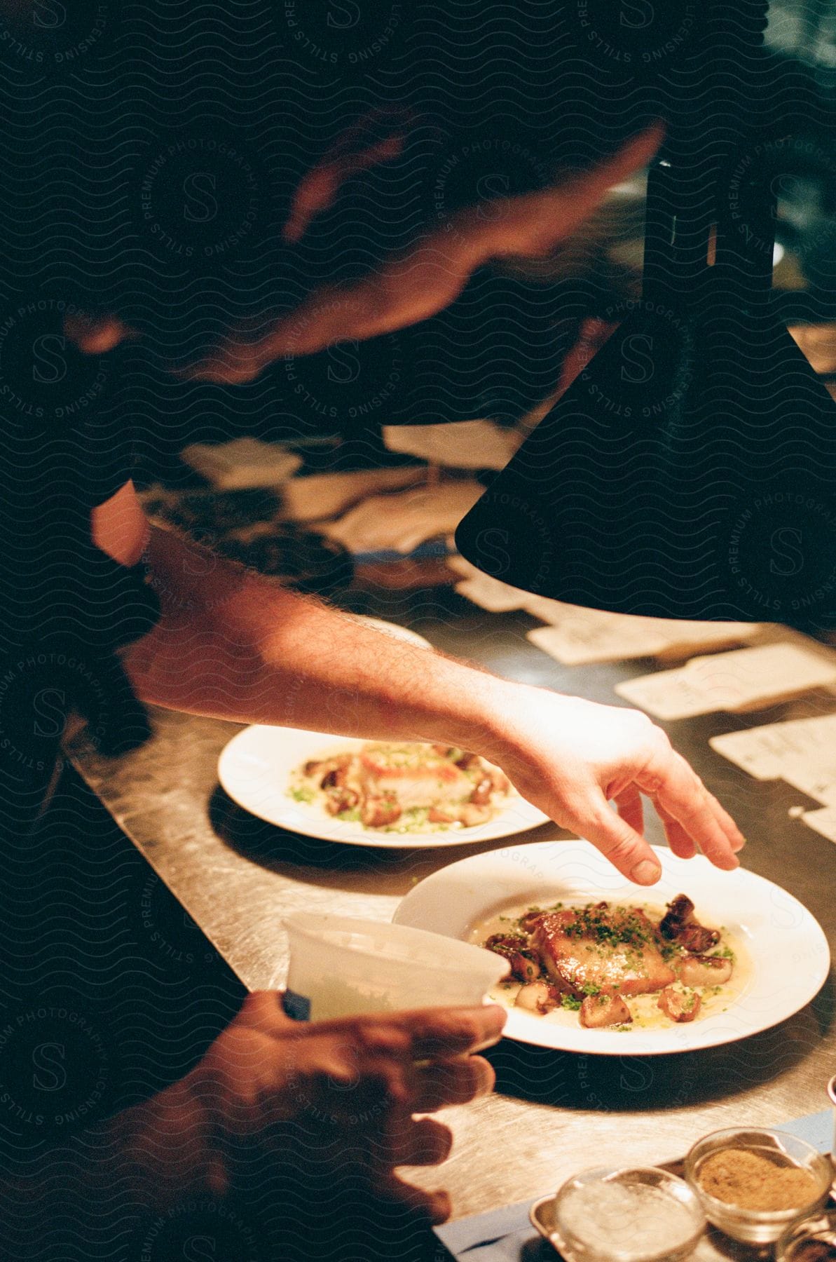 Man finishing a dish with spices, featuring salmon and white sauce.