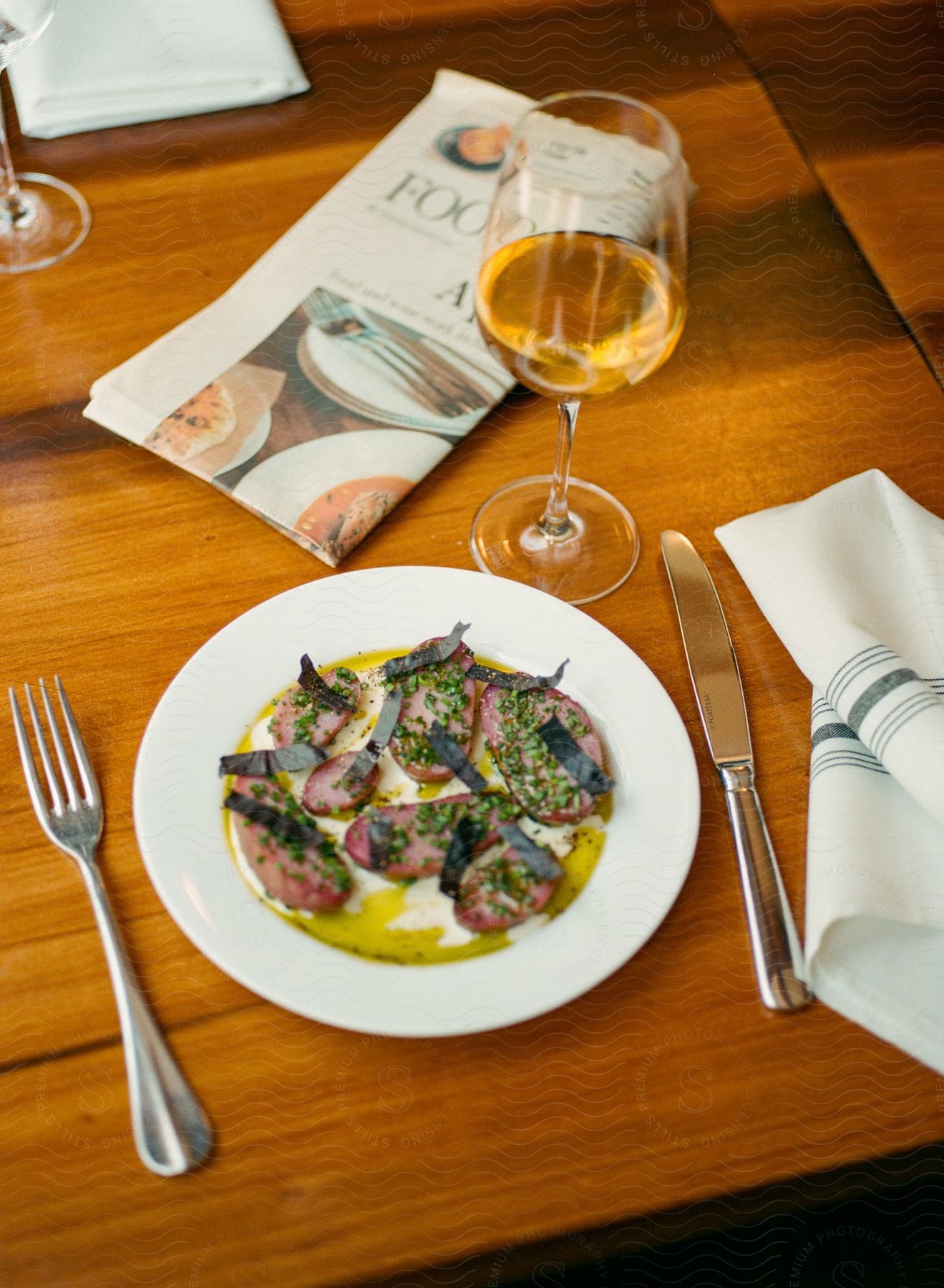 A meal sits on a table with a glass of champagne and a newspaper