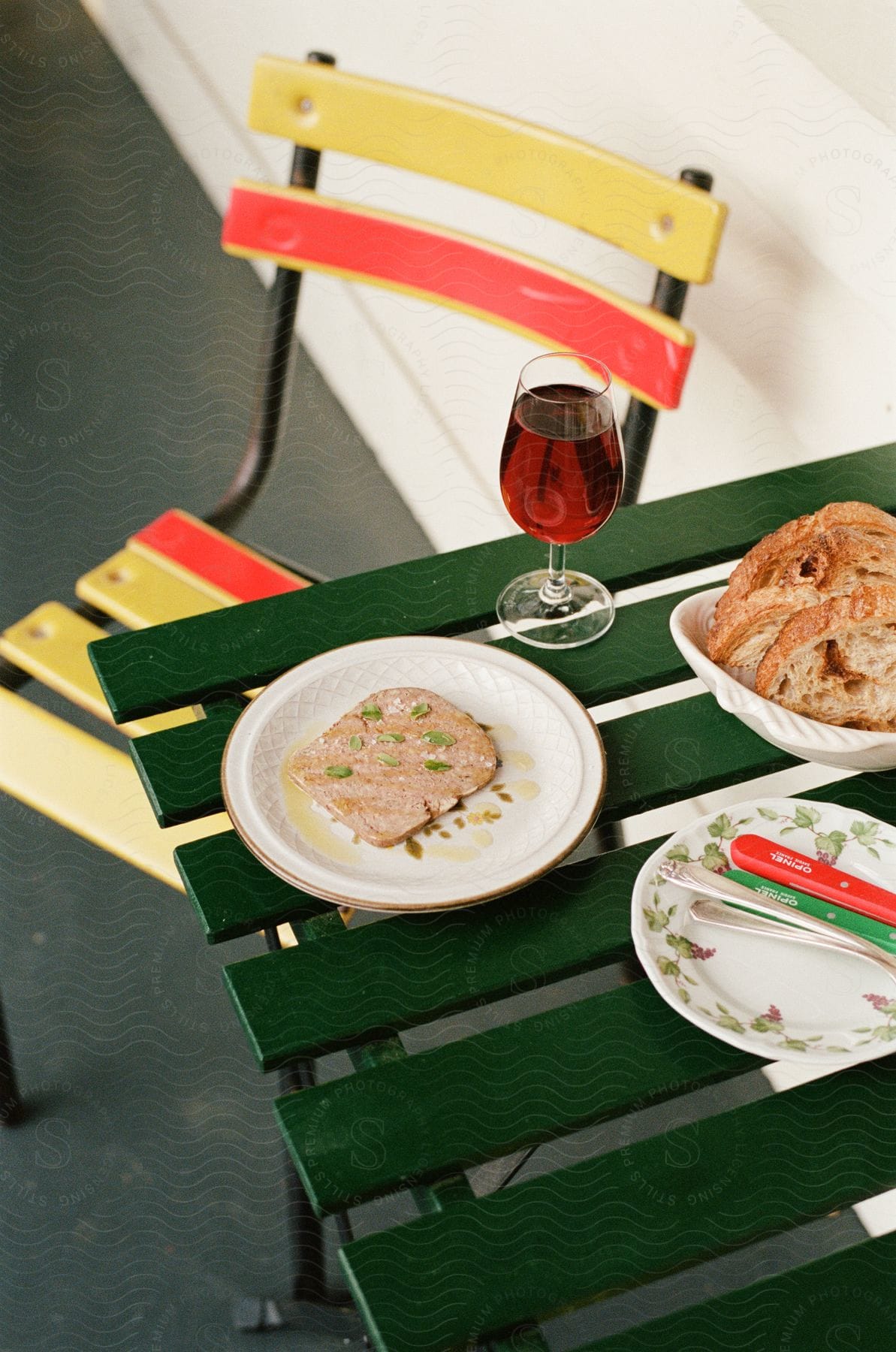 A sandwich and a glass of wine on the green wooden table.