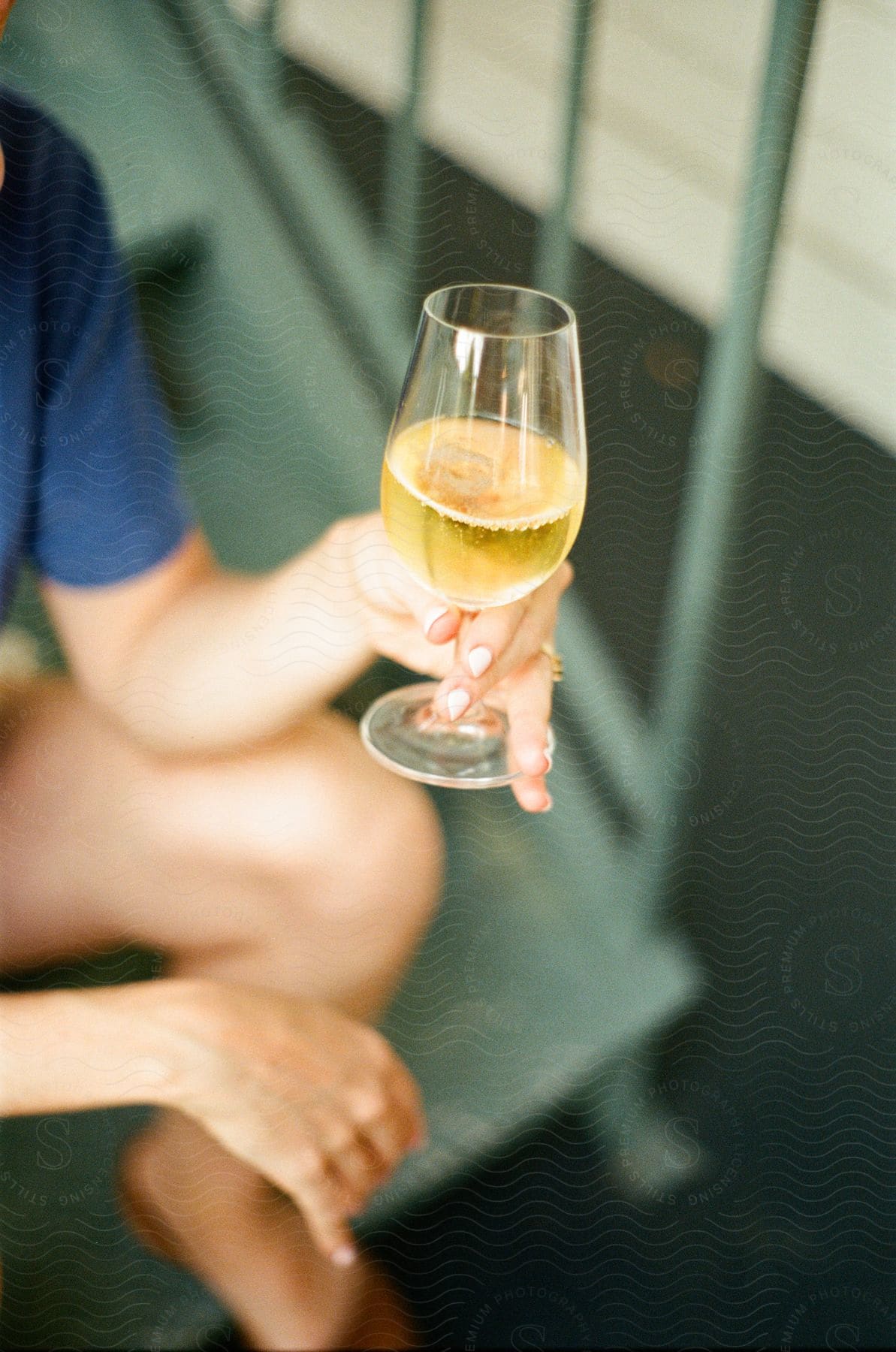 A woman wearing shorts holding a beer in a stemmed glass sitting on metal steps